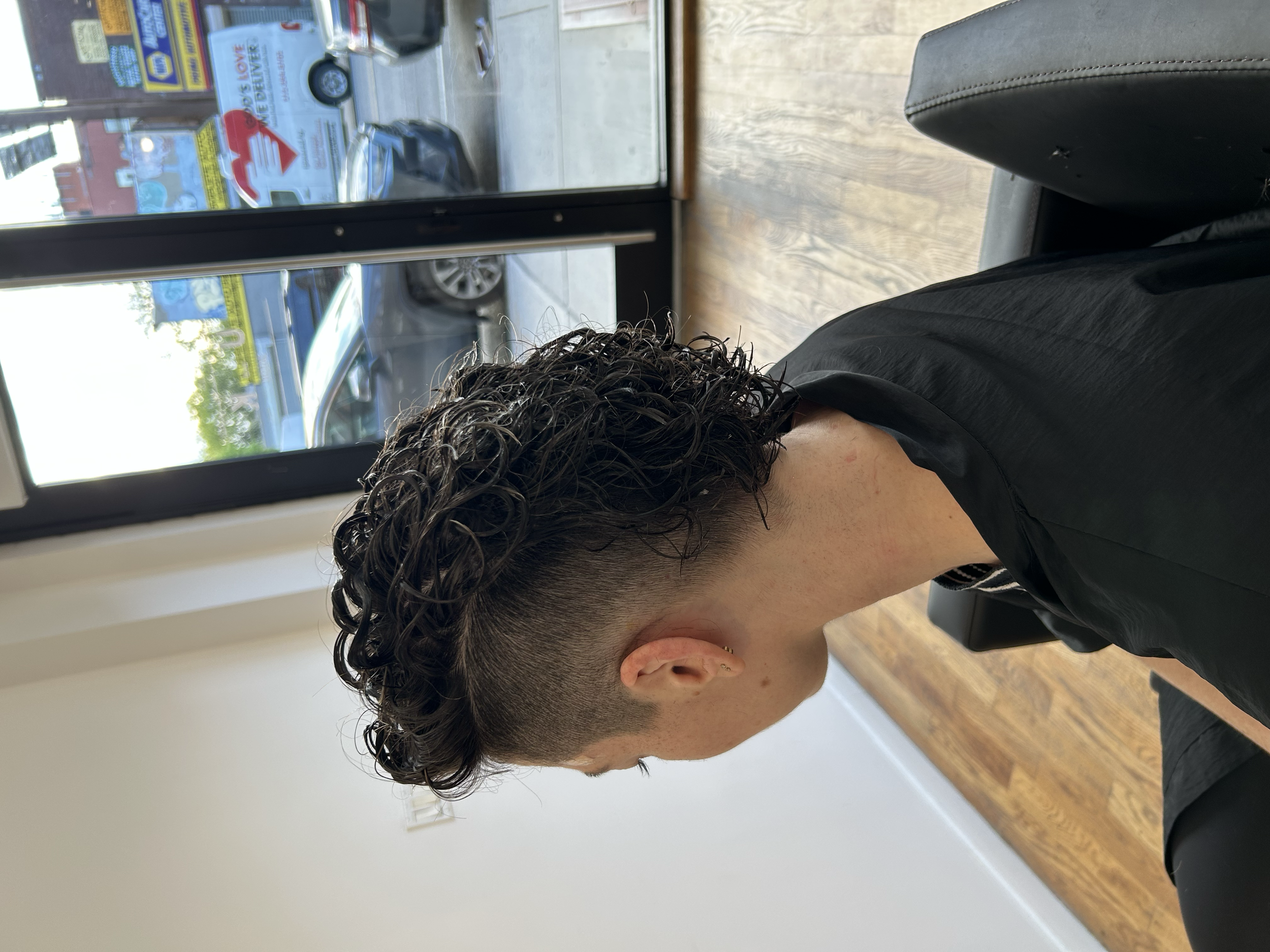 Short curly hairstyle with a close fade on the sides and defined curls on top at U&K Salon in Brooklyn.