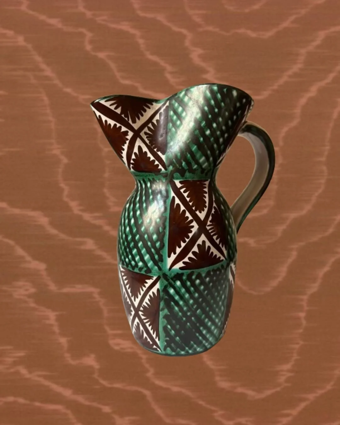 Pichet en c&eacute;ramique &eacute;maill&eacute;e, sign&eacute;, d&eacute;cor&eacute; de motifs g&eacute;om&eacute;triques et v&eacute;g&eacute;taux dans une palette de verts, bruns et ivoire.
La forme galb&eacute;e et l&rsquo;anse dessin&eacute;e av