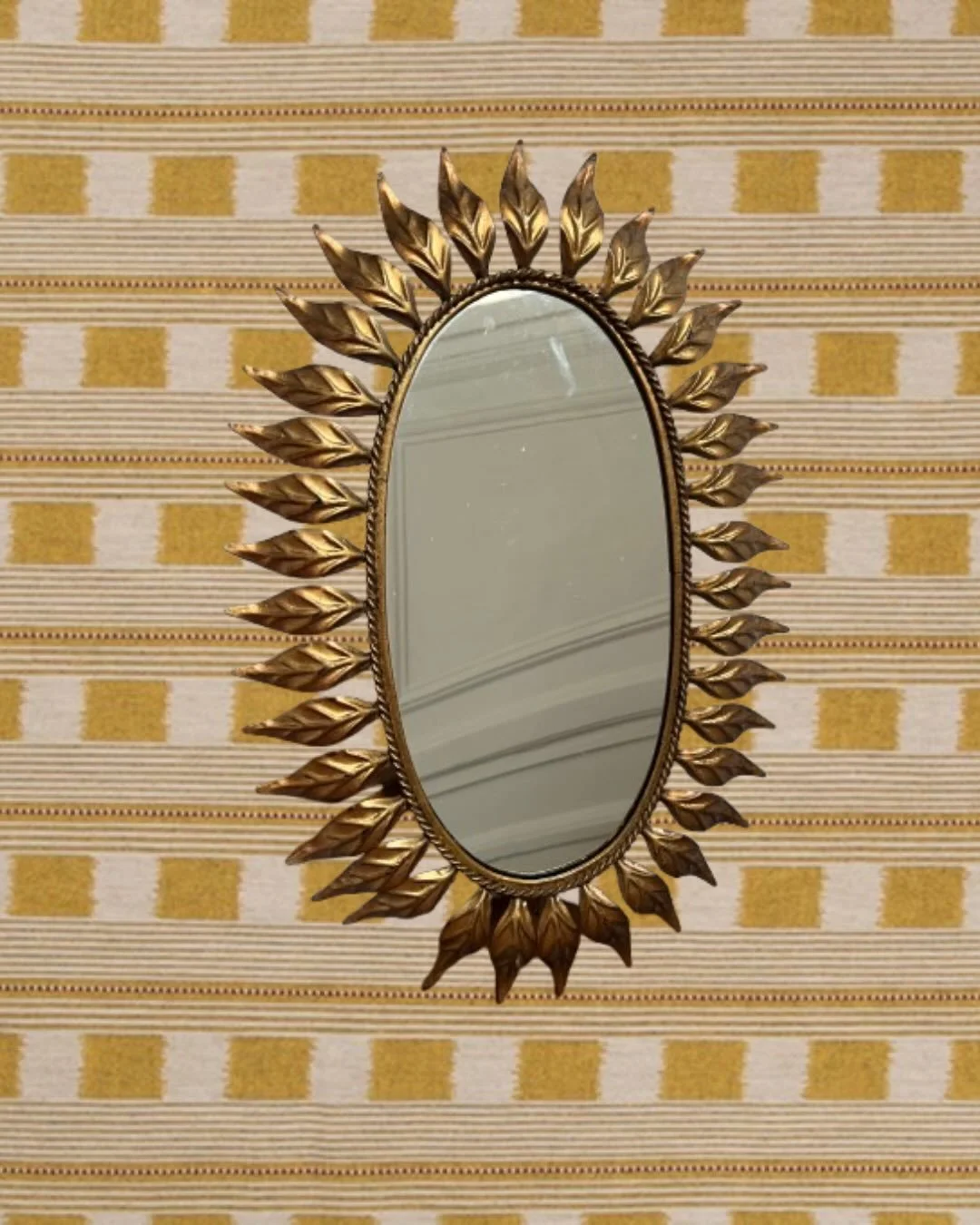 Miroir vintage dor&eacute; Sunburst, design ann&eacute;es 60.
Encadrement orn&eacute; de feuilles en relief, en m&eacute;tal dor&eacute; patin&eacute;.

En tr&egrave;s bon &eacute;tat vintage, quelques l&eacute;g&egrave;res marques du temps 

Pi&egra