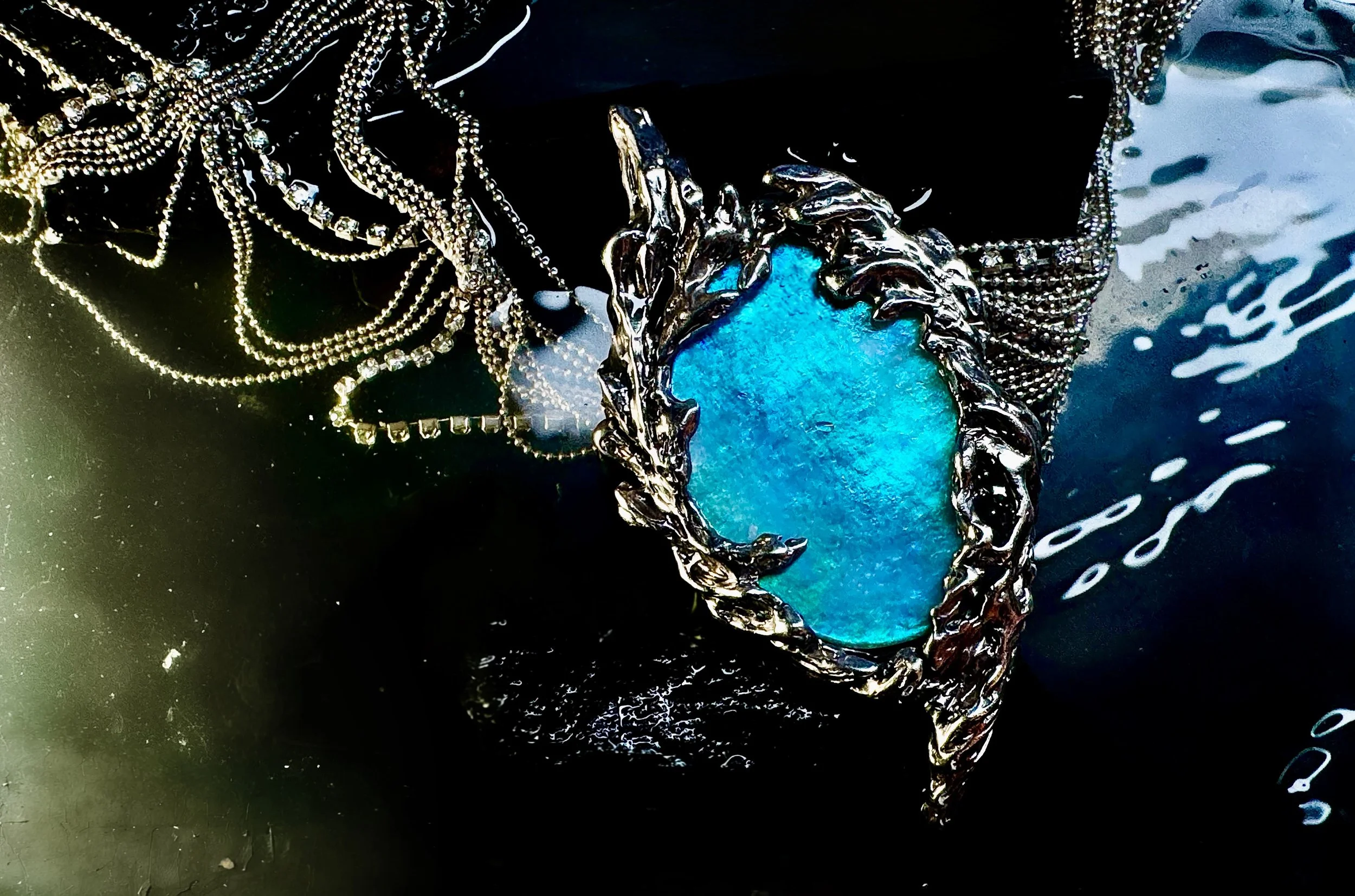Large Australian aurora blue black opal set in sculptural white gold flame necklace with multiple chains  floating in water. Statement art jewelry.