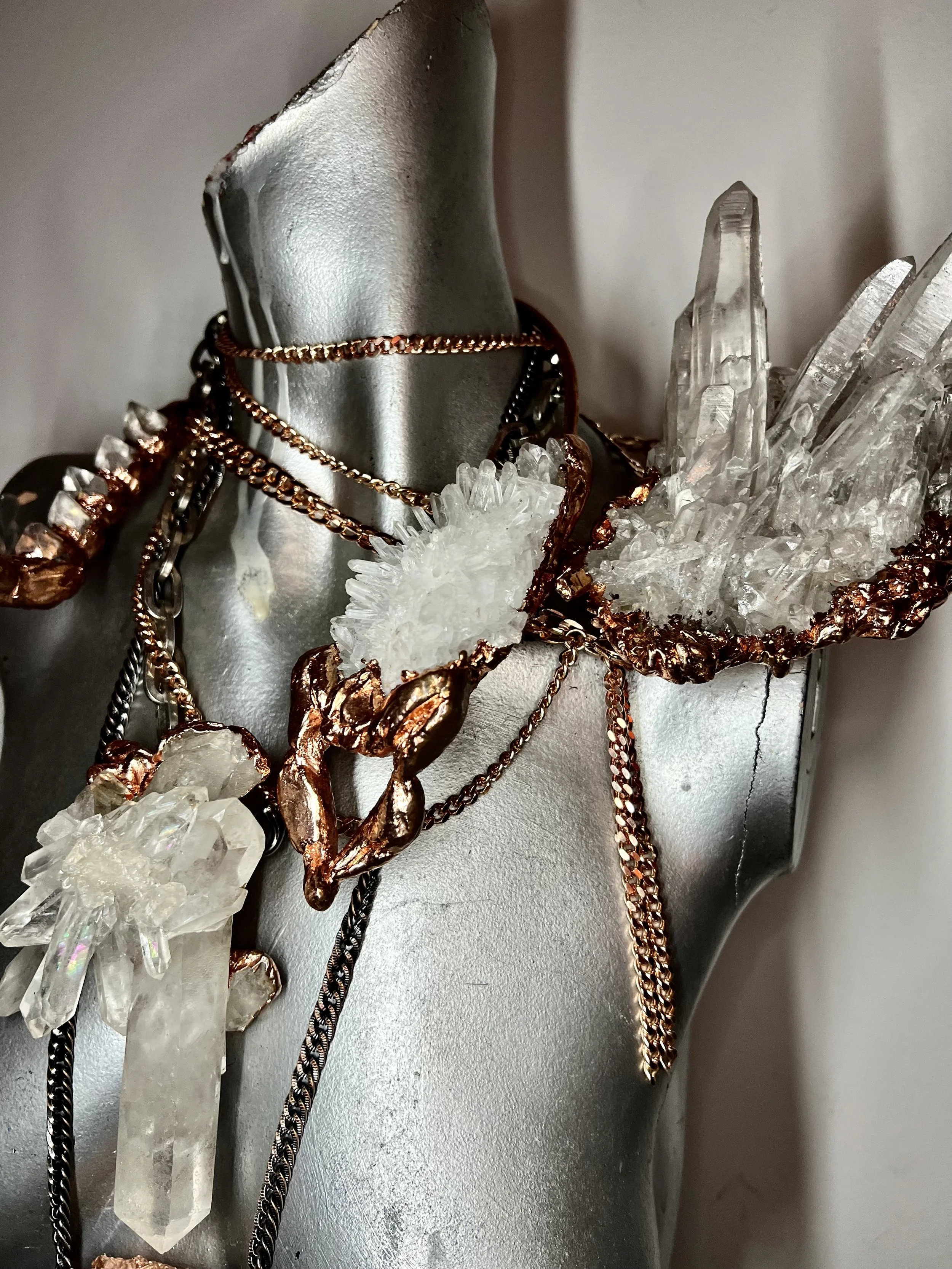 Statement Illumin Designs crystal quartz Necklaces with crystal shoulder epilette draped over a silver mannequin bust.