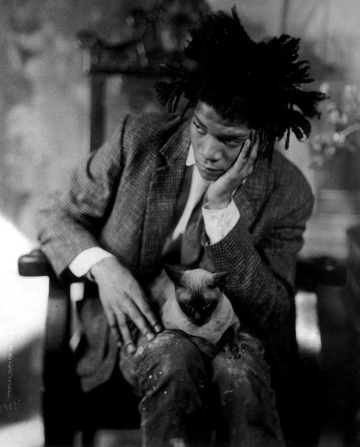 Black and white photo of Artist Jean-Michel Basquiat and his siamese cat