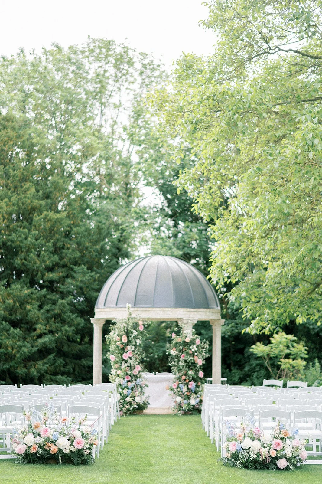 Summer garden wedding ceremony with floral meadow aisle and soft pastel flower pillars.