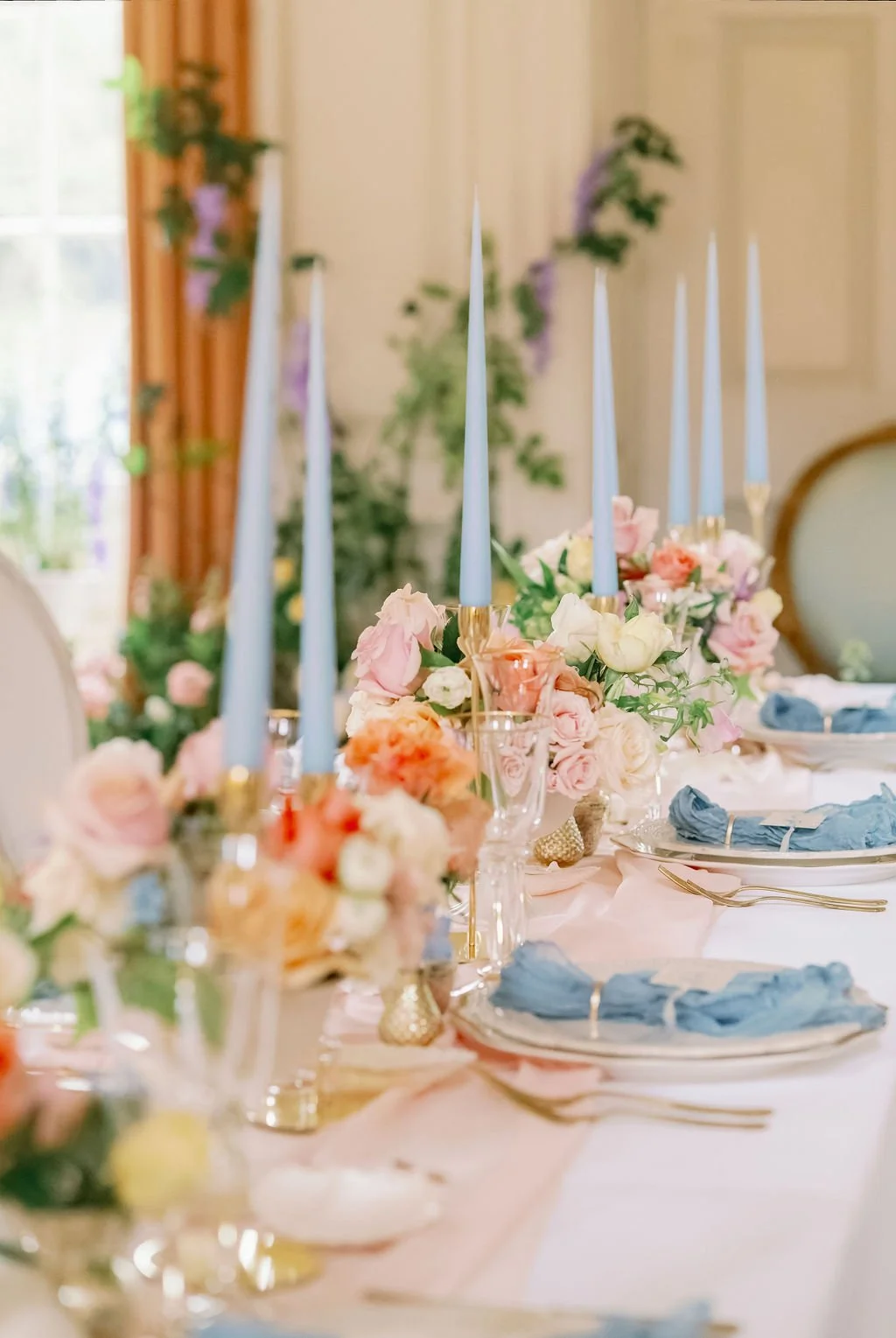 Elegant table setting with pastel flowers, blue candles, and blue napkins