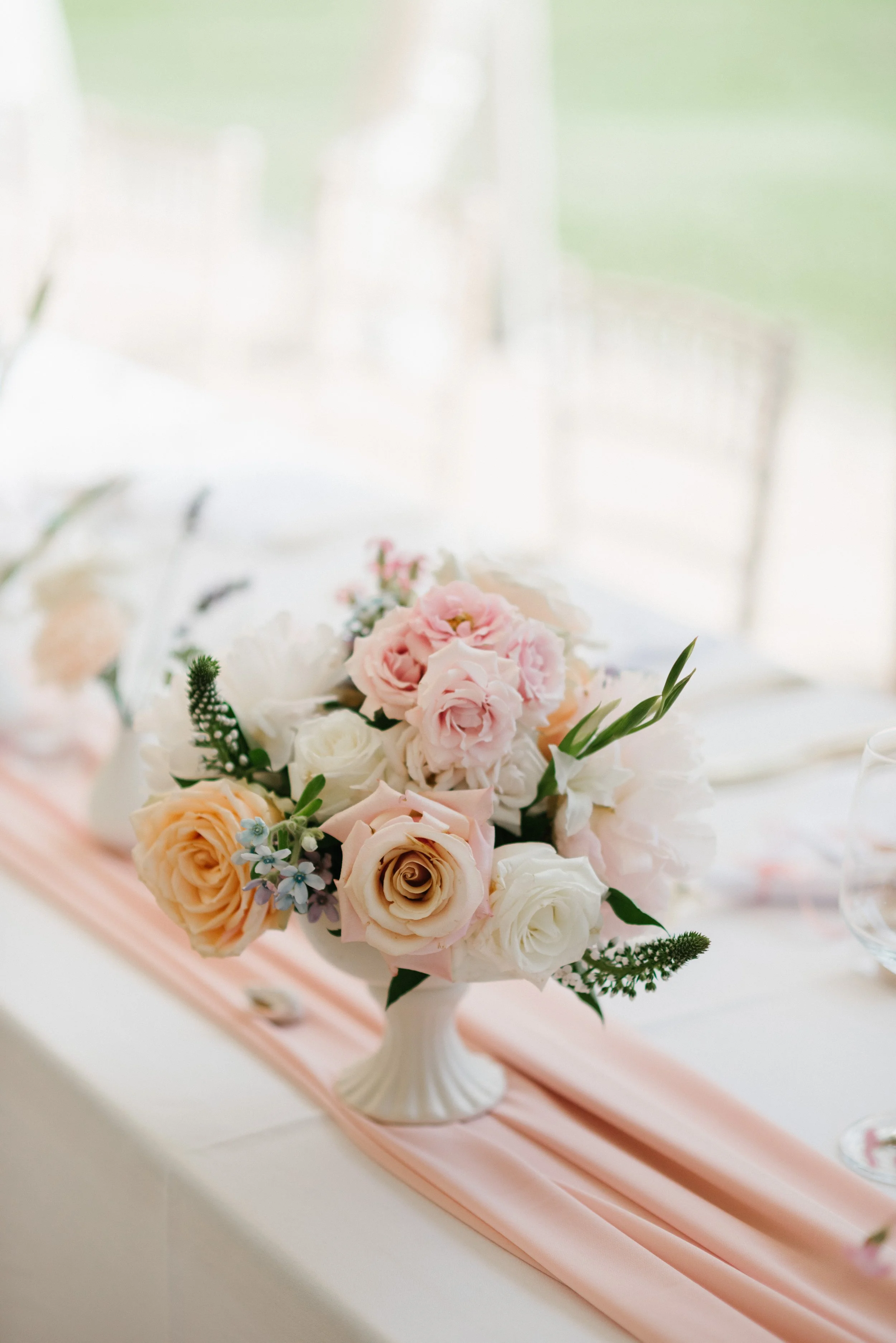 Elegant summer flower arrangement in a footed bowl with blush, peach, and garden-inspired blooms.
