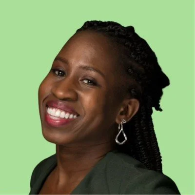 Woman with braid black hair in dark green dress smiling in front of a light green background