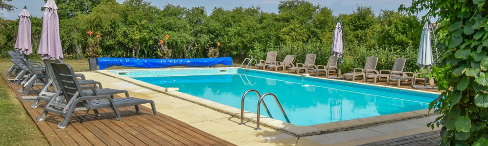 Large outdoor pool surrounded by sun loungers on decking