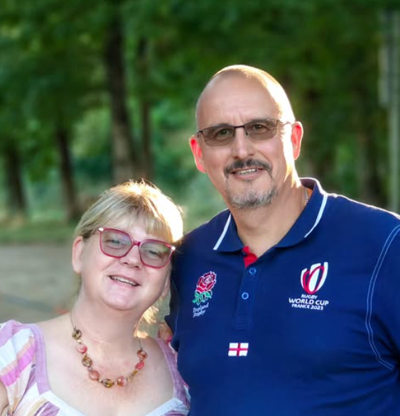 Couple smiling in front of forest background at golden hour