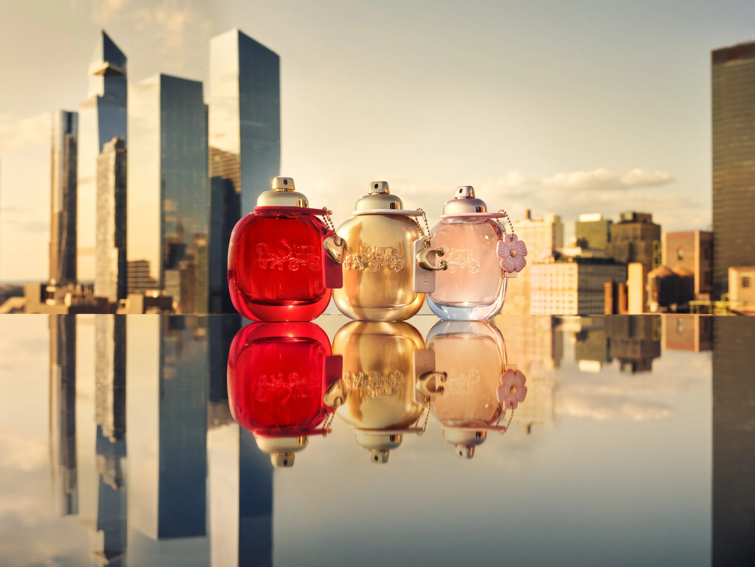 Coach Love, Floral and Gold fragrance bottles with NYC skyline backdrop, photographed by Cass Bird