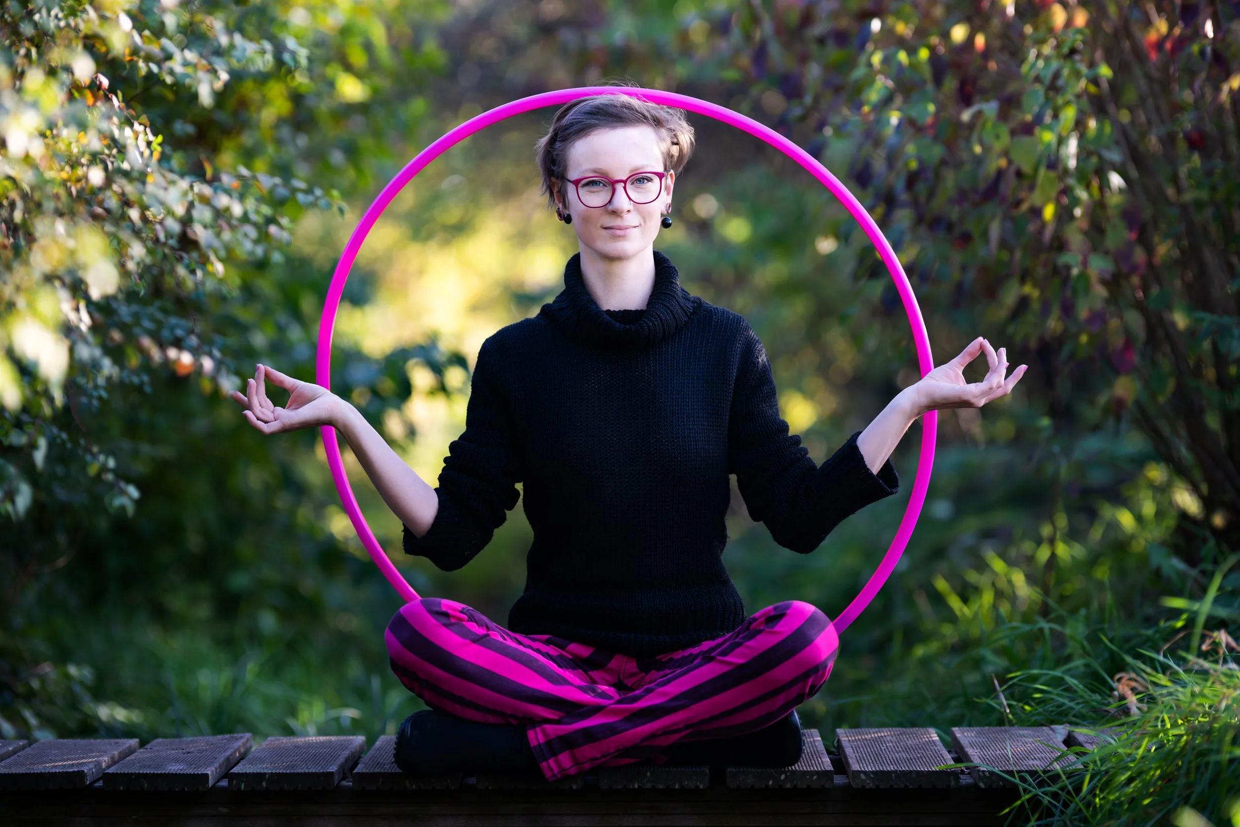Elena Tinkloh, psychologist and flow artist, sitting inside a pink hula hoop in a meditative pose