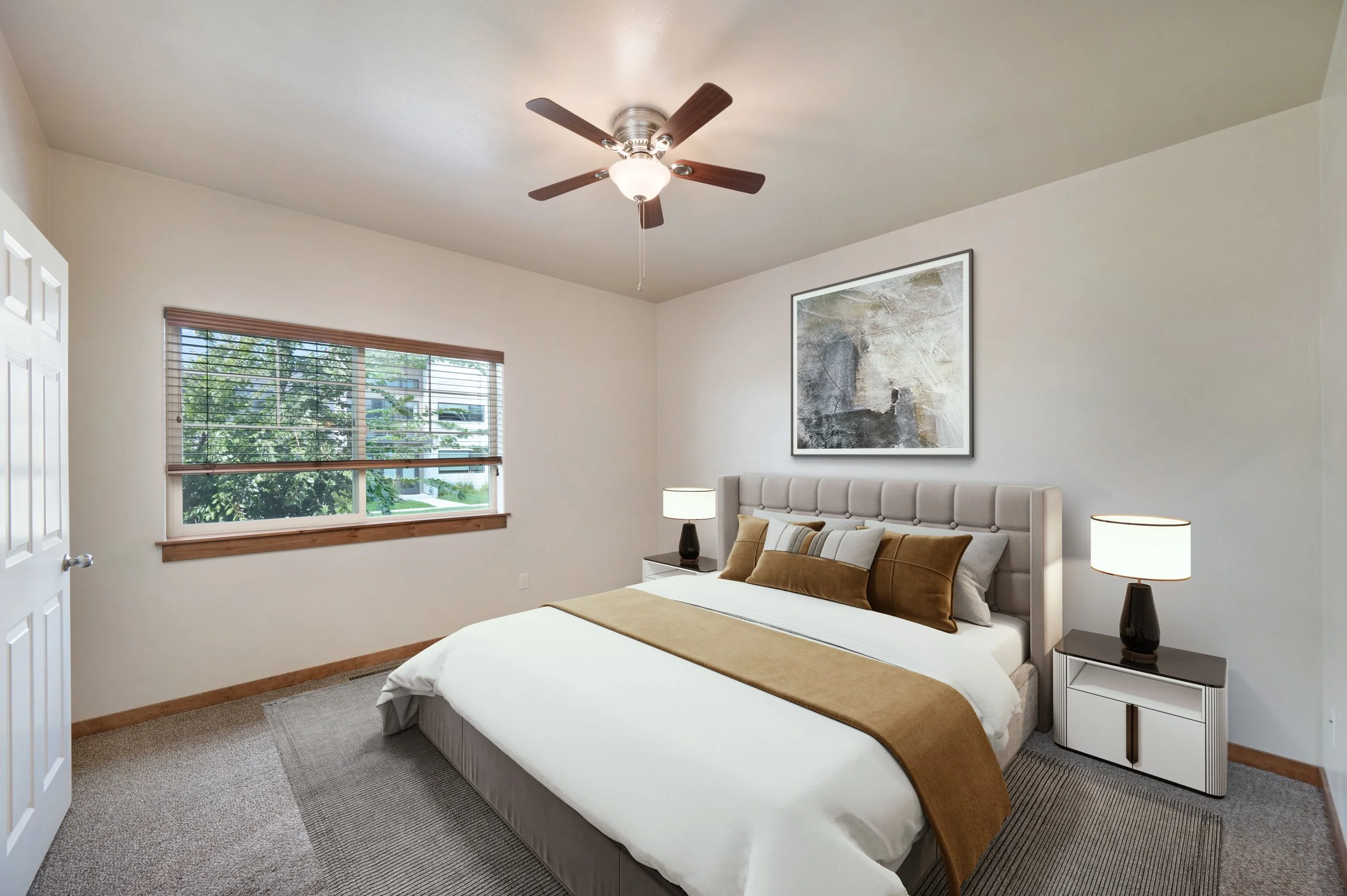 A modern bedroom with a large bed, nightstands with lamps, a window with blinds, and a ceiling fan.