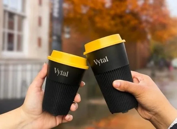 two vytal cups cheersing. Black cup and yellow lid