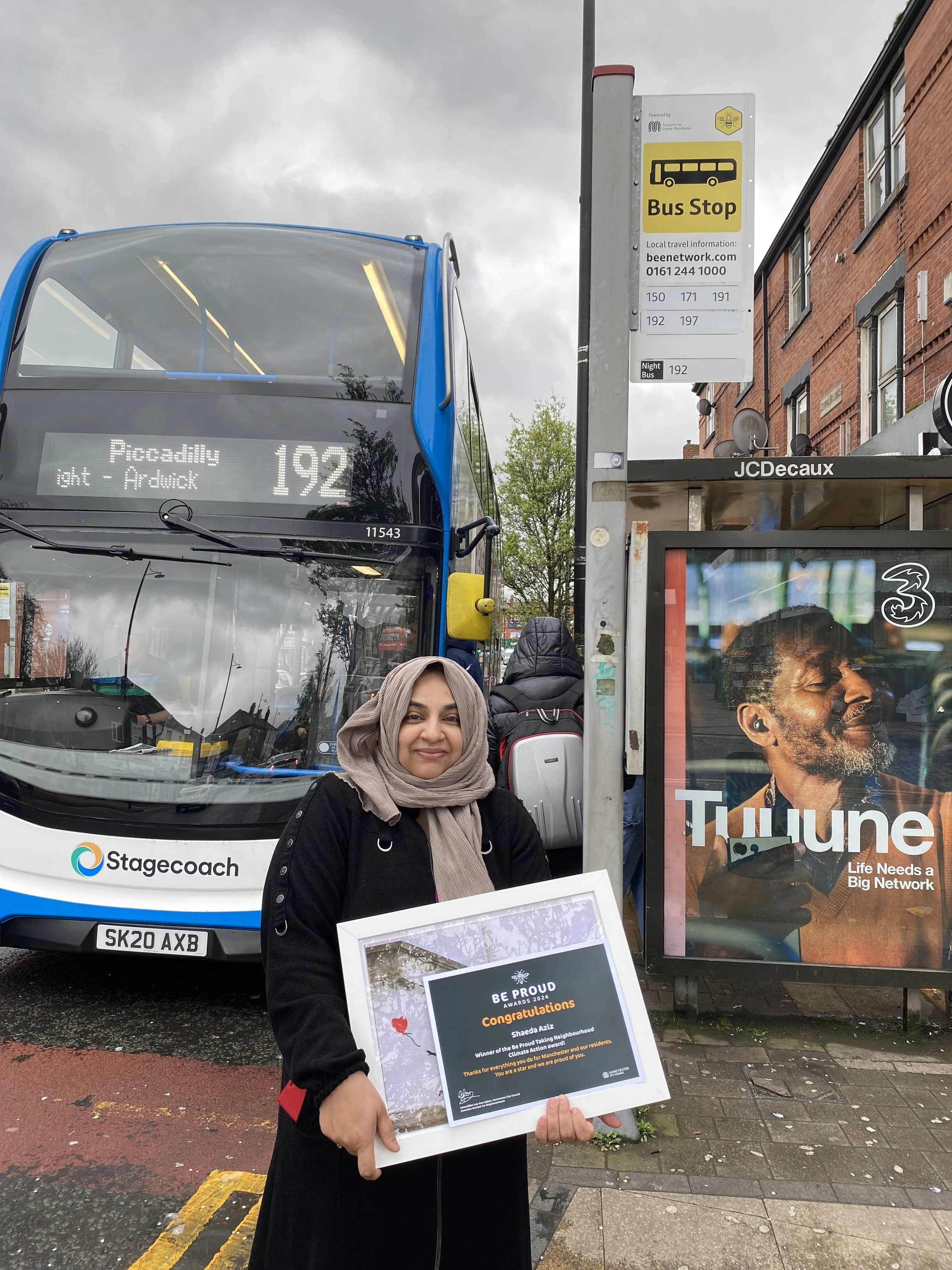 Shaeda holding her Be Proud award in front of bus