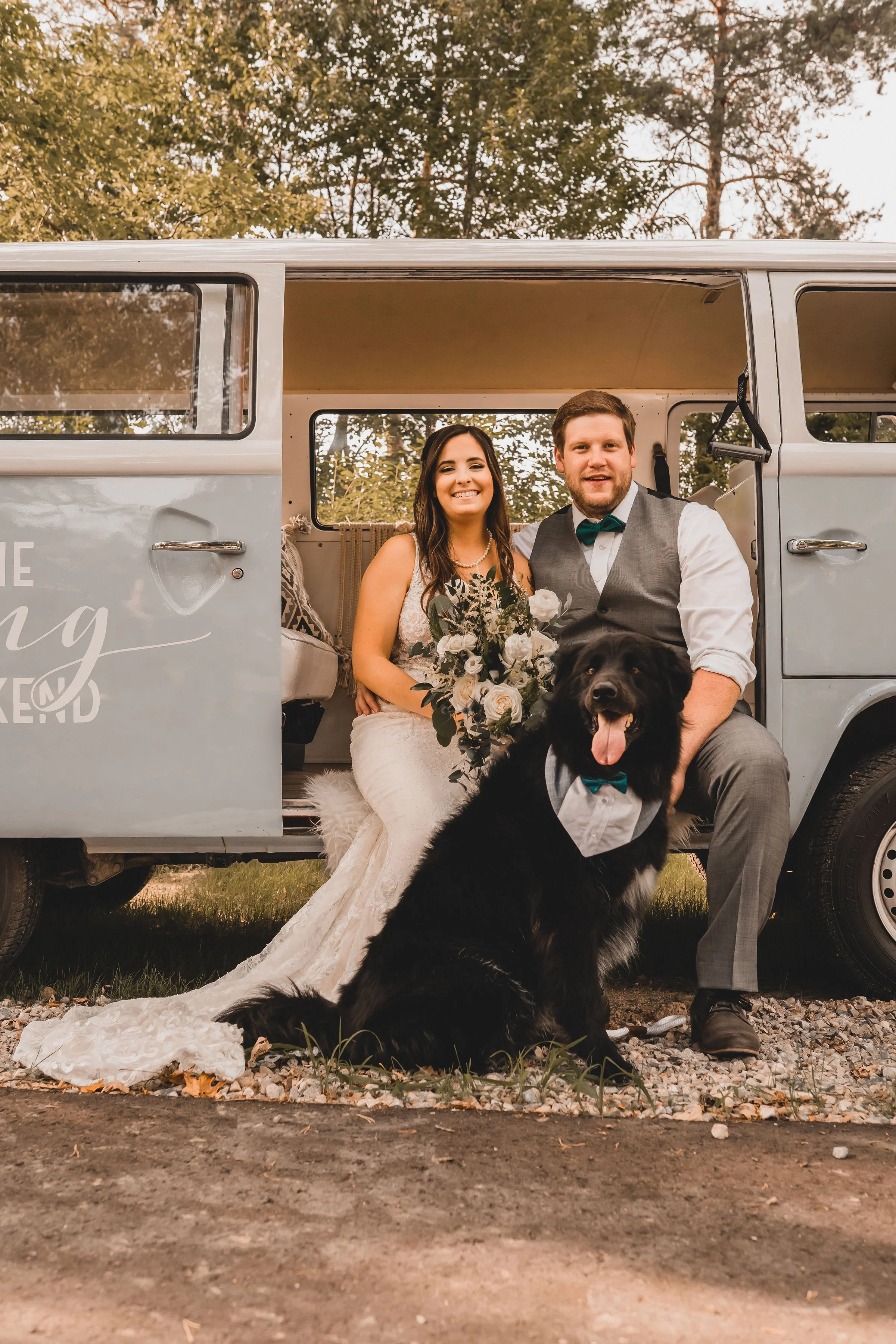 Pup Oakley poses with his parents on their wedding day in a vintage VW bus. Black Dog Weddings wedding dog attendant