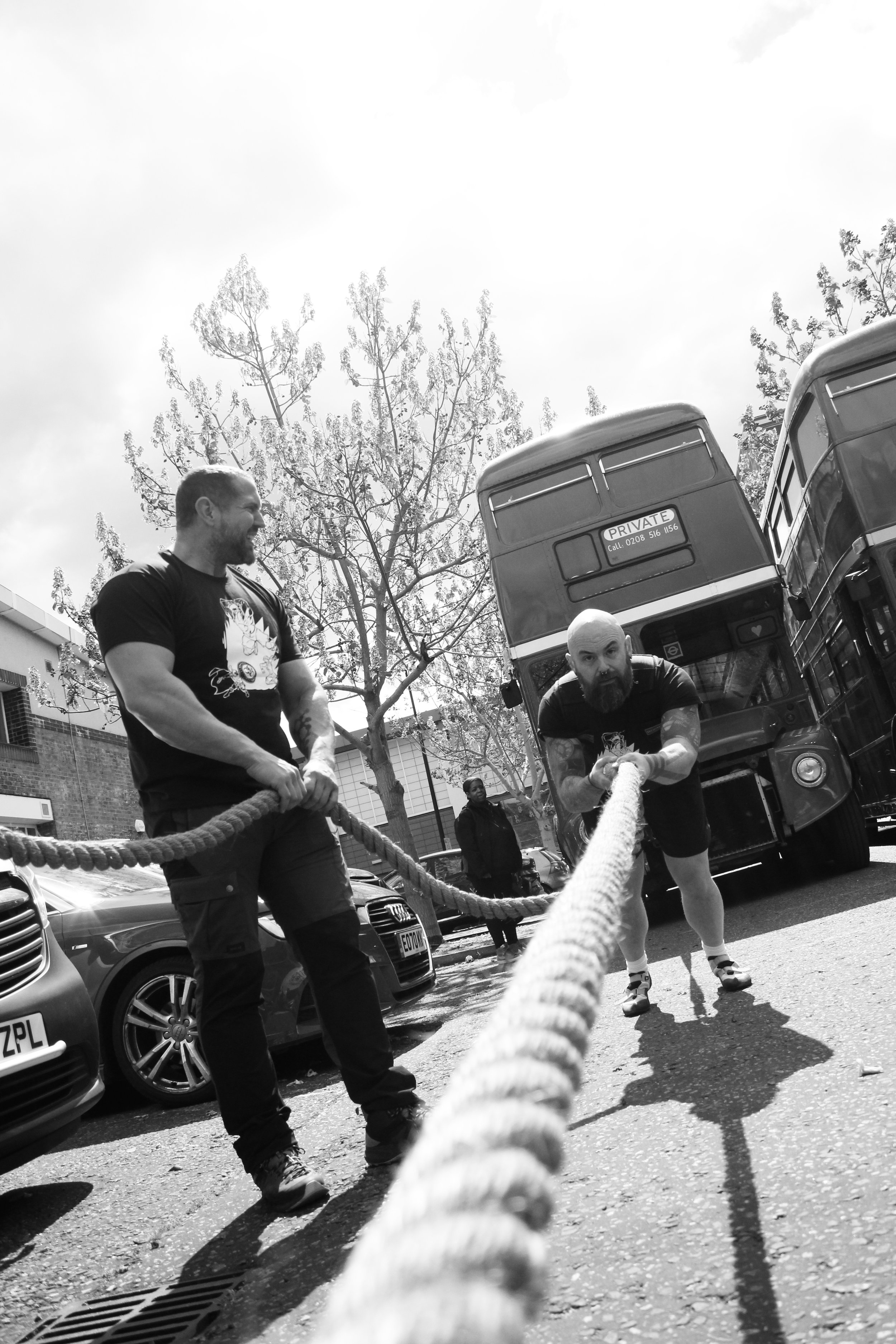 A strongman competitor pulling a vintage double decker, Routemaster London bus at a Strongman competition in south east London