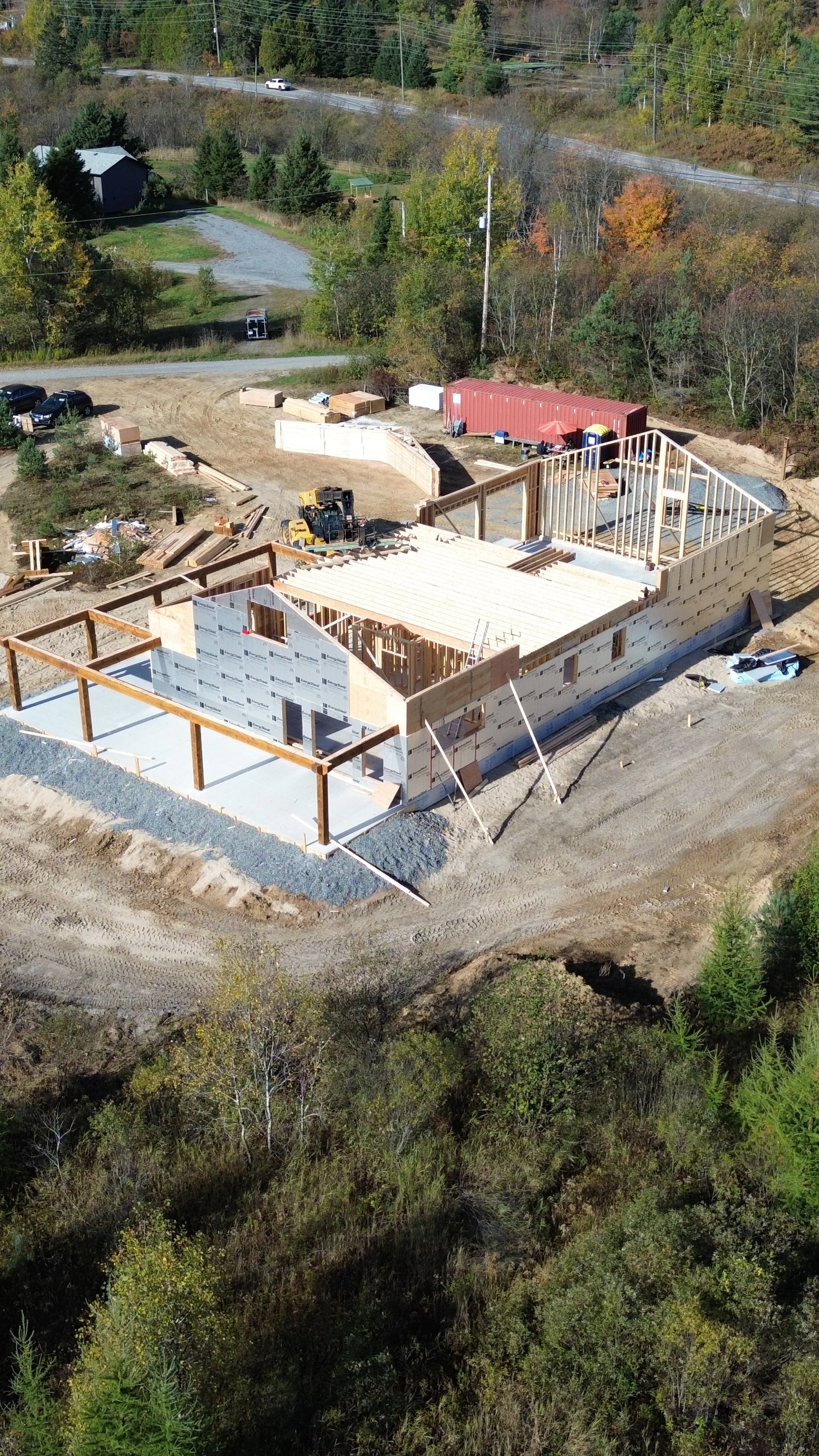 Under construction house in snowy landscape with partially completed roof and visible framing.
