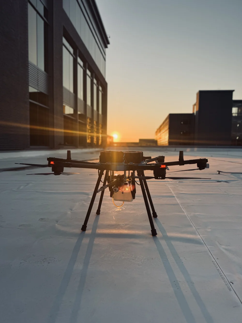 Cleaning drone staged on a commercial rooftop at sunset