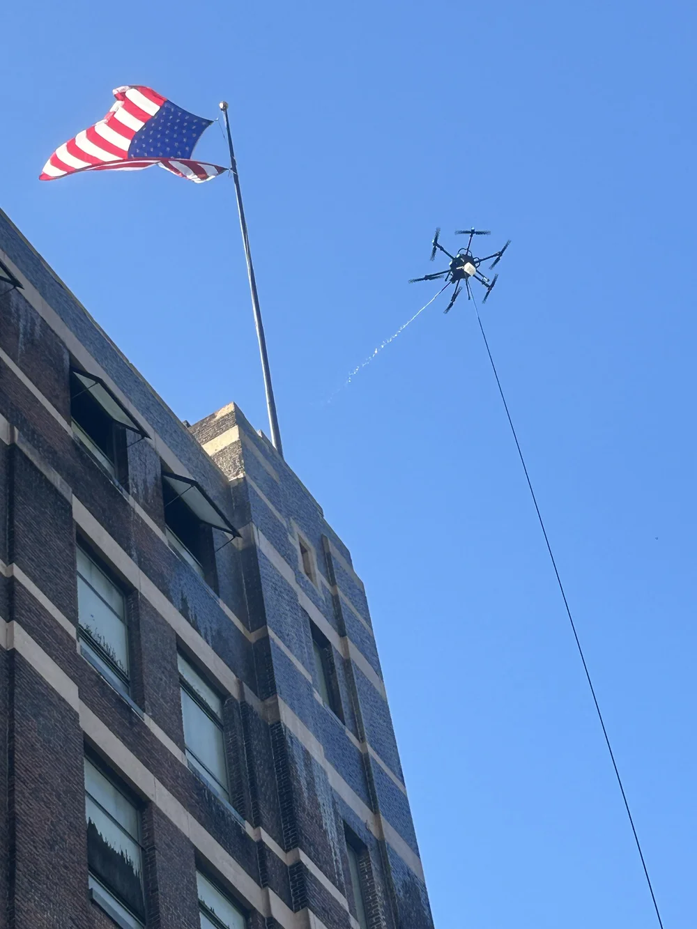 Cleaning drone flying near the top of a multi-story commercial building