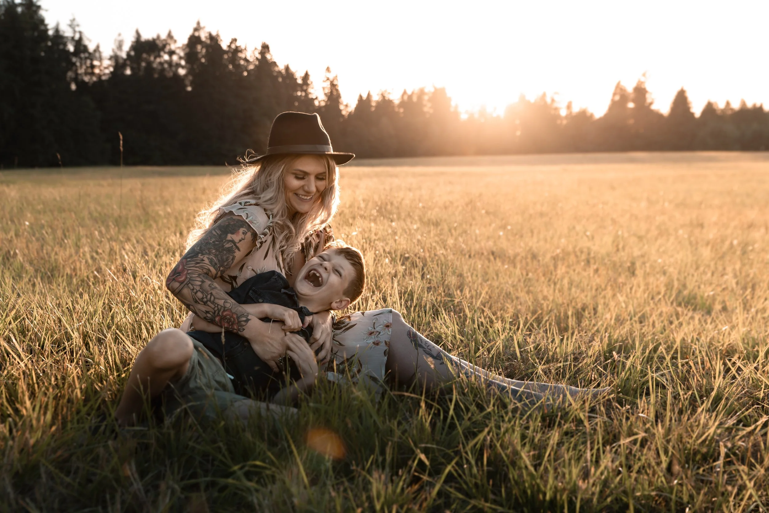 Mother laughing with her young son in a golden field during a family photo session in Vancouver Washington, a meaningful Mother’s Day gift idea.