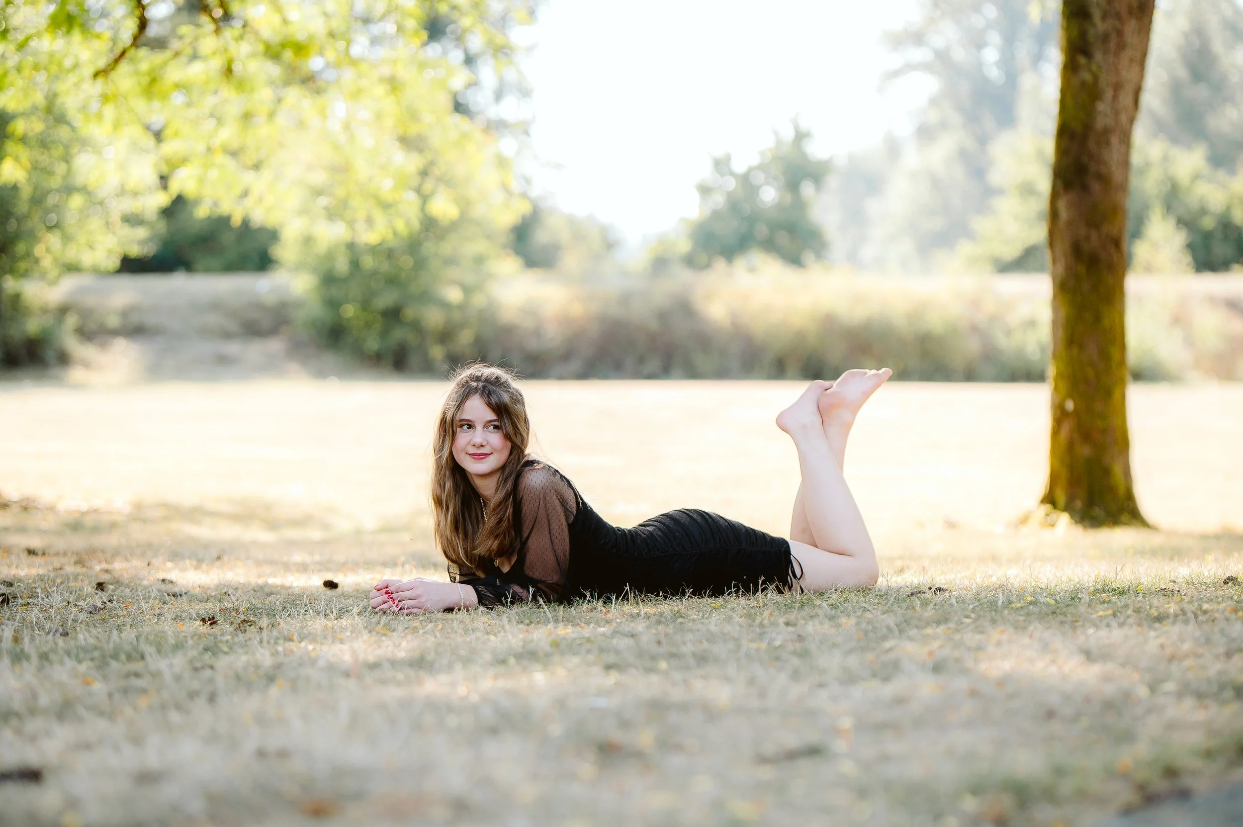 Creative senior portrait session in Vancouver Washington featuring a playful pose in a natural outdoor environment with warm afternoon light.