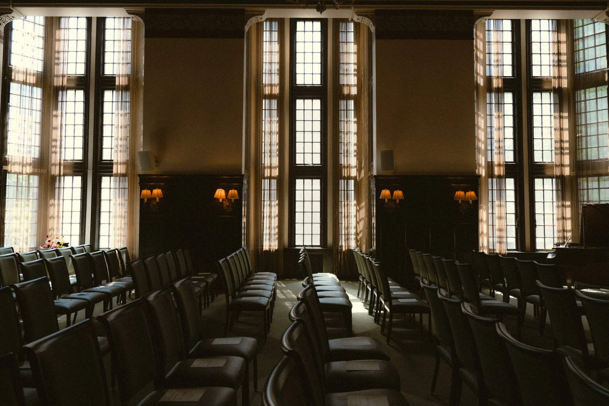 Seating area inside the University Club of Portland ballroom in front of three floor-to-ceiling historic windows with natural light and elegant wedding venue architecture