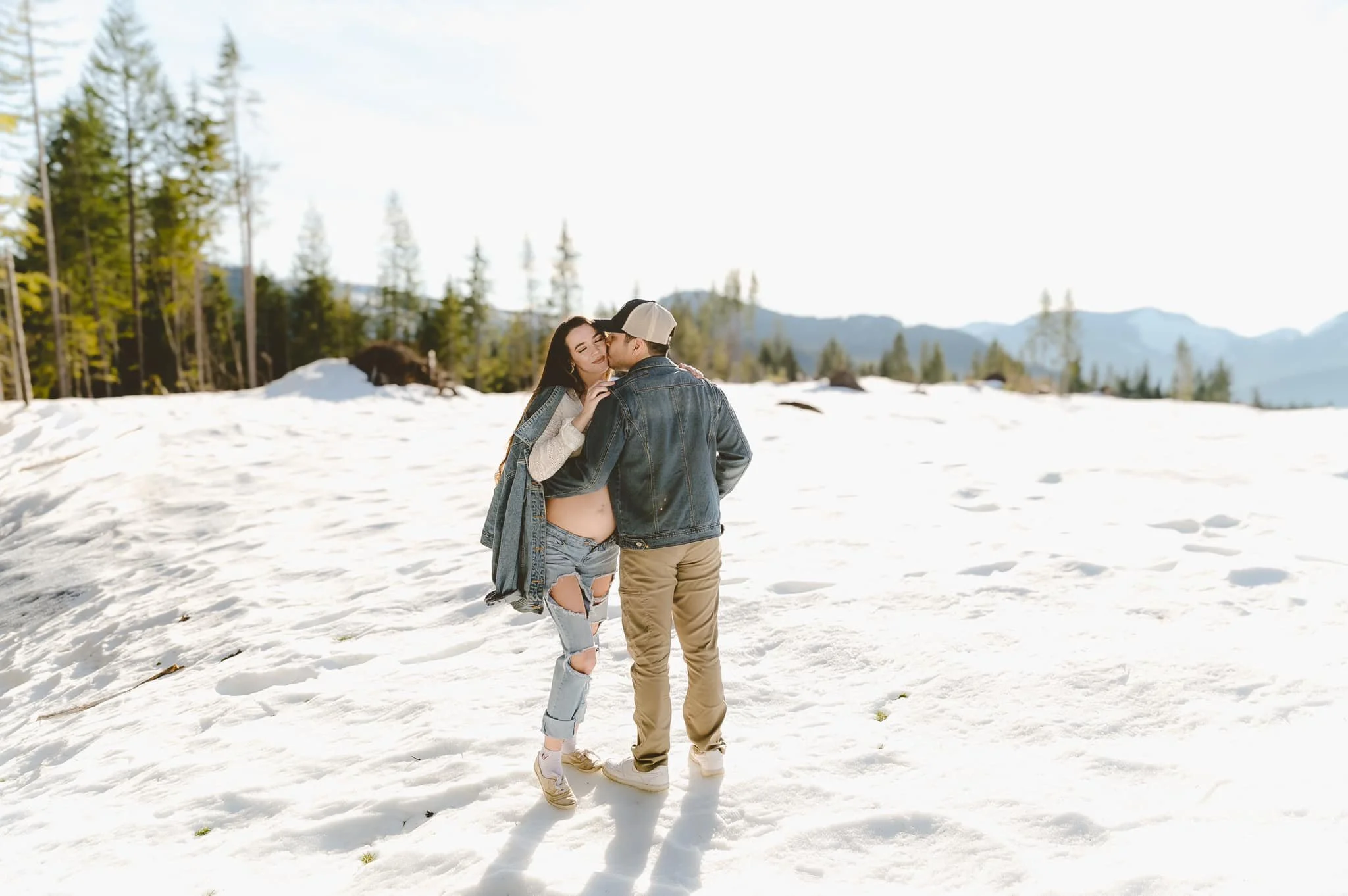 Expectant parents sharing a quiet moment during a relaxed winter maternity photo session outdoors