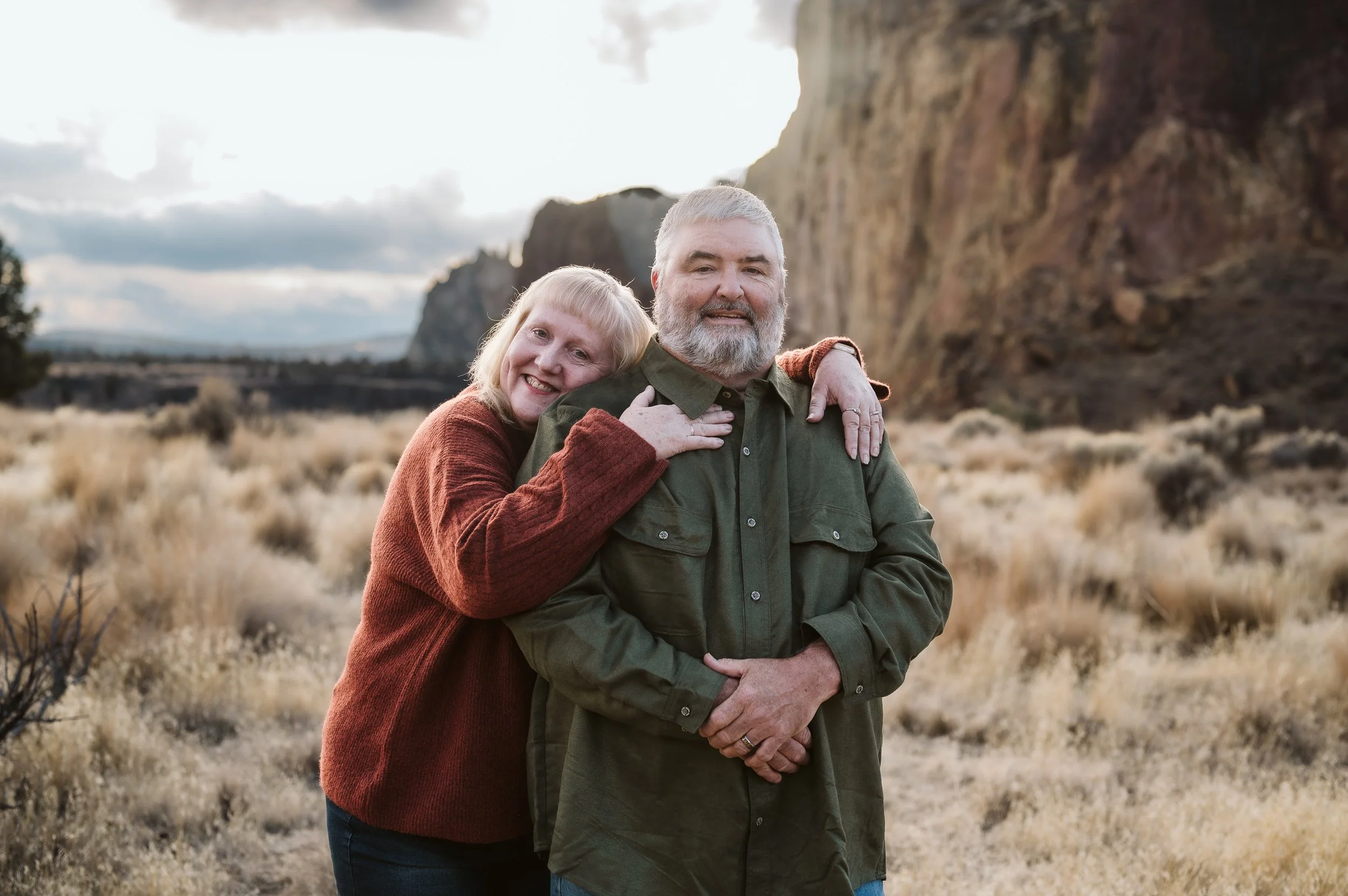 Multi-generation family photography in Oregon featuring a grandparent and child embracing in a rugged natural landscape.
