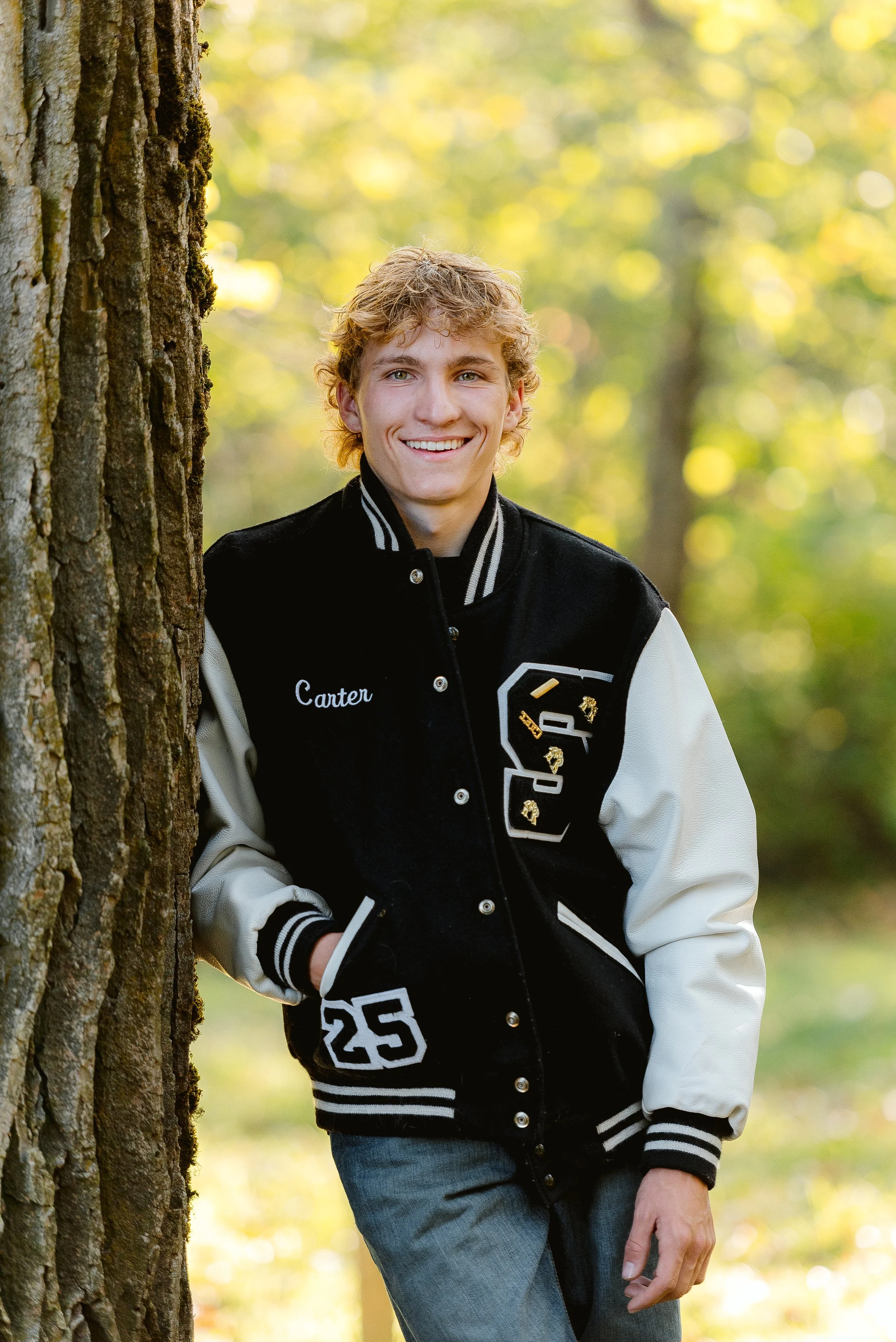 Graduation portrait session in Vancouver Washington featuring a high school senior wearing a letterman jacket during an outdoor shoot.