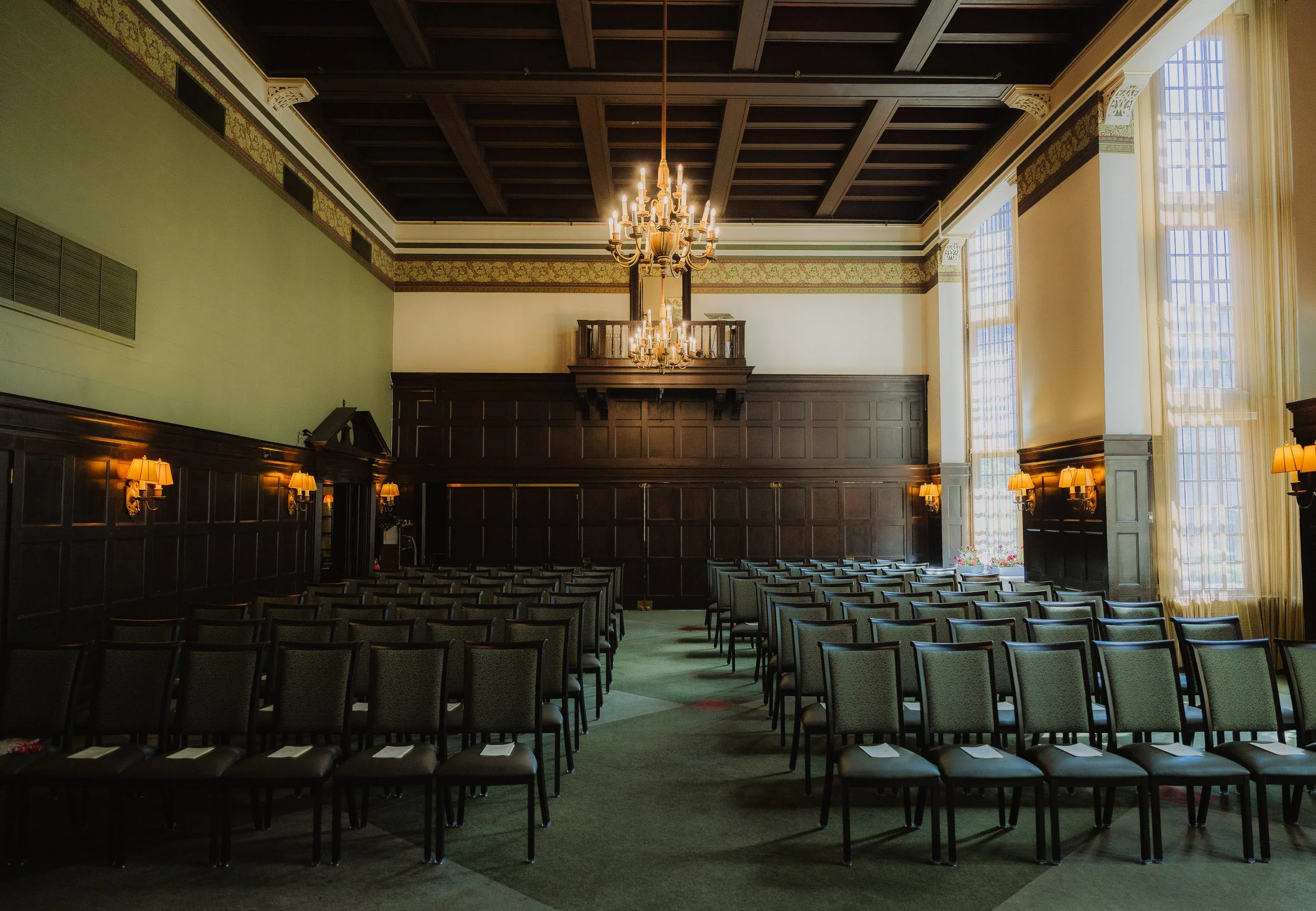 Elegant interior of the University Club of Portland ballroom featuring historic architecture, chandelier lighting, tall windows, and classic wedding ceremony setup