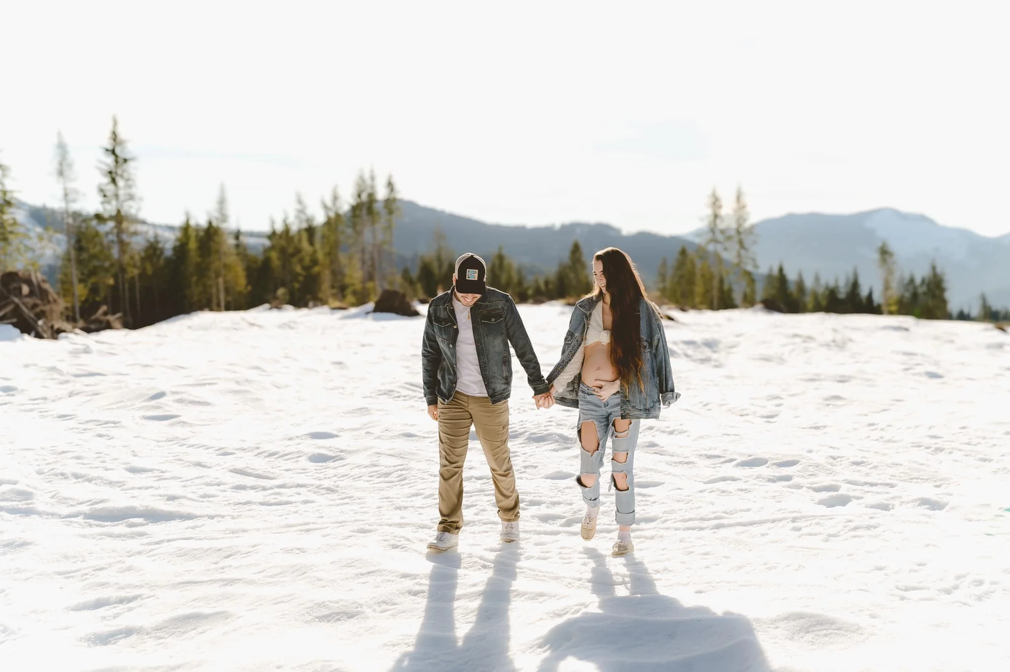 Outdoor winter maternity session featuring an expecting couple walking hand in hand in the snow, photographed by a Vancouver, Washington maternity photographer in the Pacific Northwest.