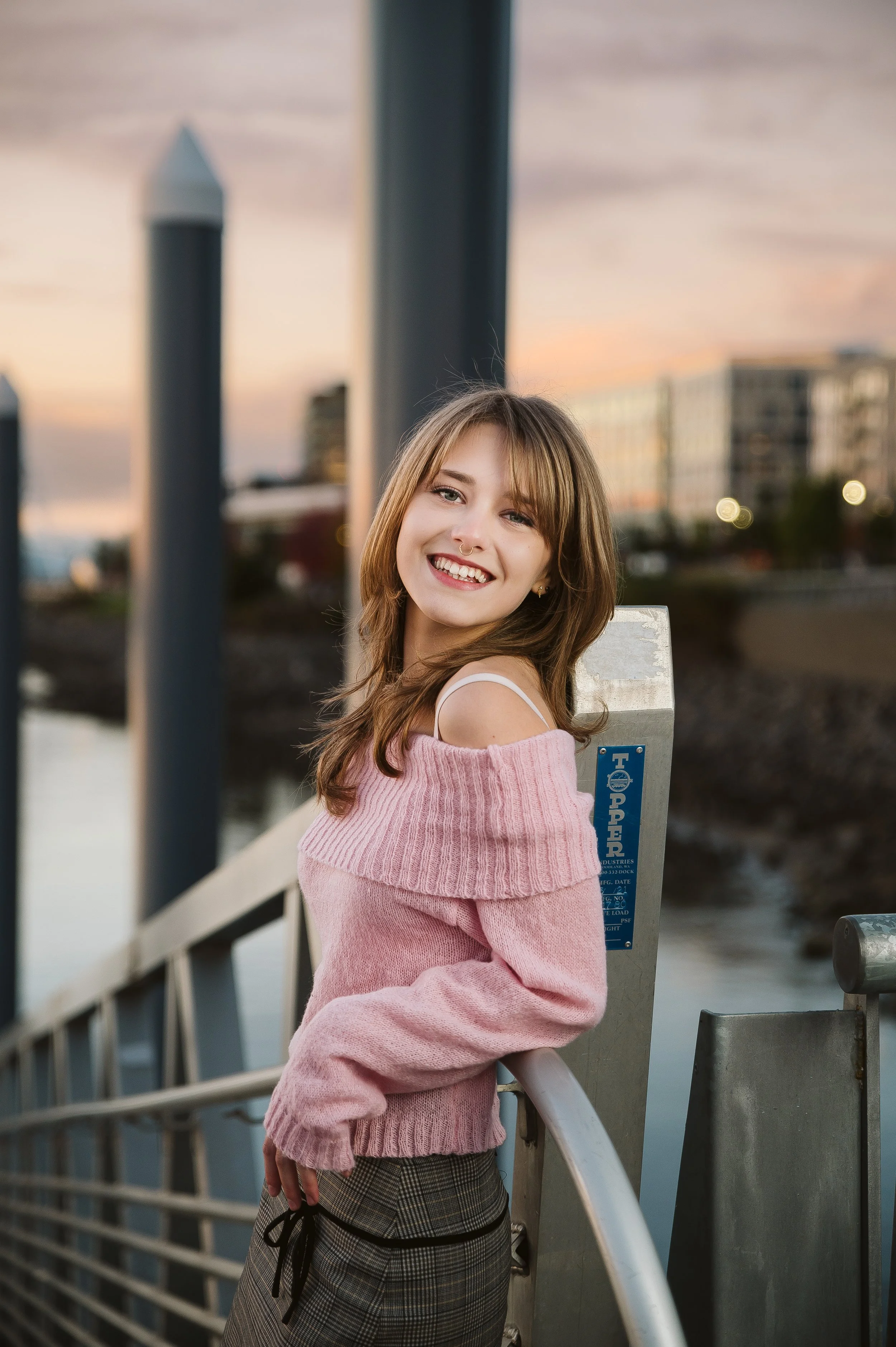 High school senior in a pink sweater photographed at sunset near the Vancouver Washington waterfront