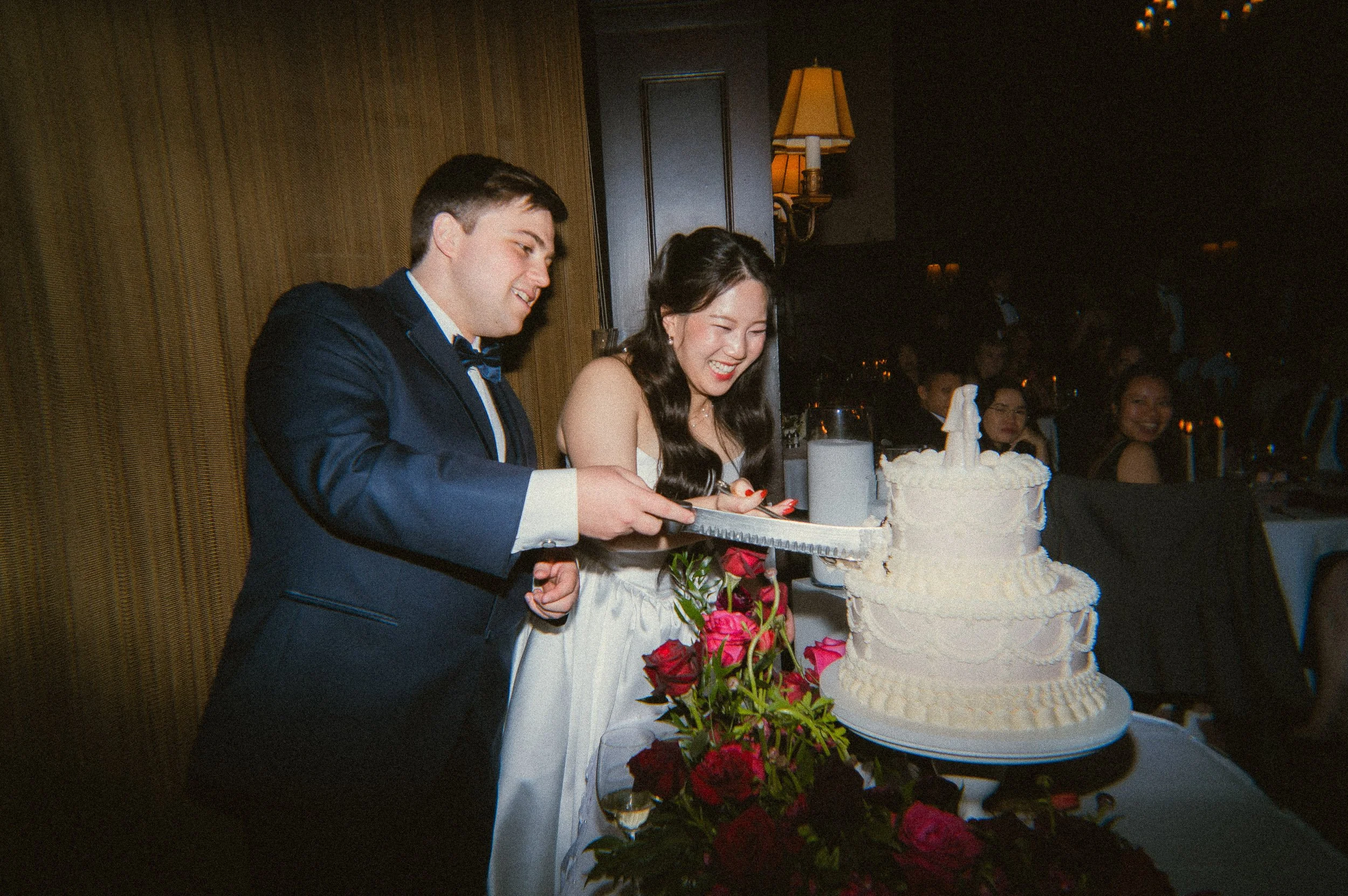 Bride and groom cutting wedding cake during reception at the University Club of Portland with elegant ballroom lighting and romantic wedding celebration