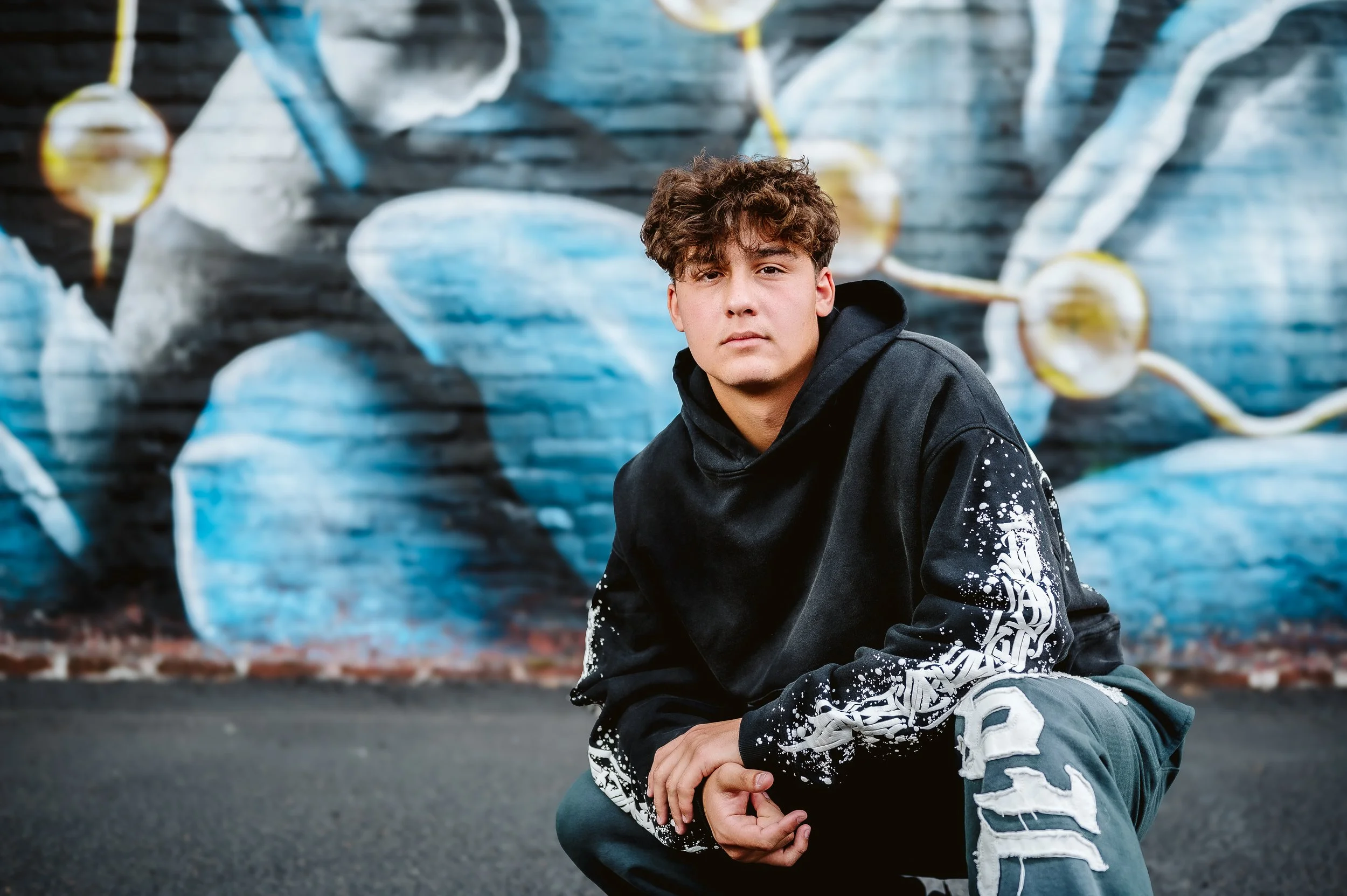 Urban senior portraits in Portland, Oregon capturing relaxed, confident expression with artistic city murals.