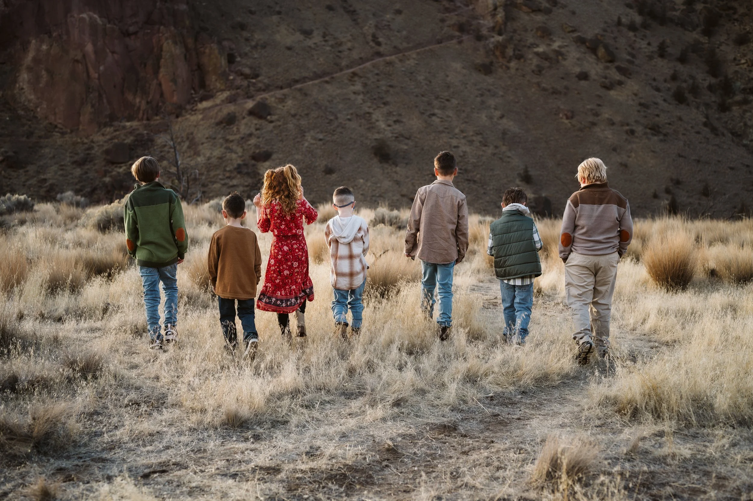Lifestyle family photography in Oregon capturing children walking together through an open landscape during a documentary-style session.