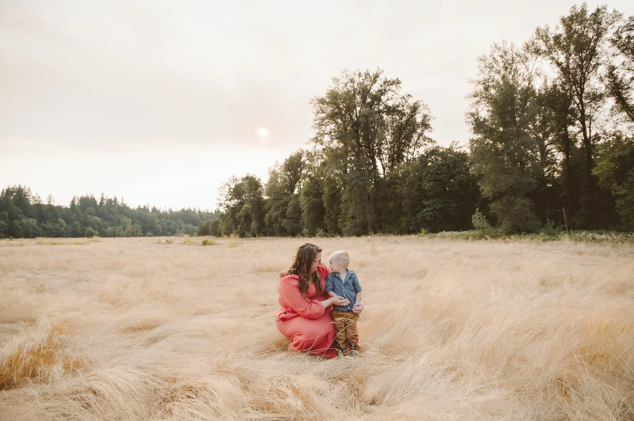 Mother and son portrait in a golden field at sunset, showing a quiet connection between parent and child, photographed by a Vancouver Washington family photographer.
