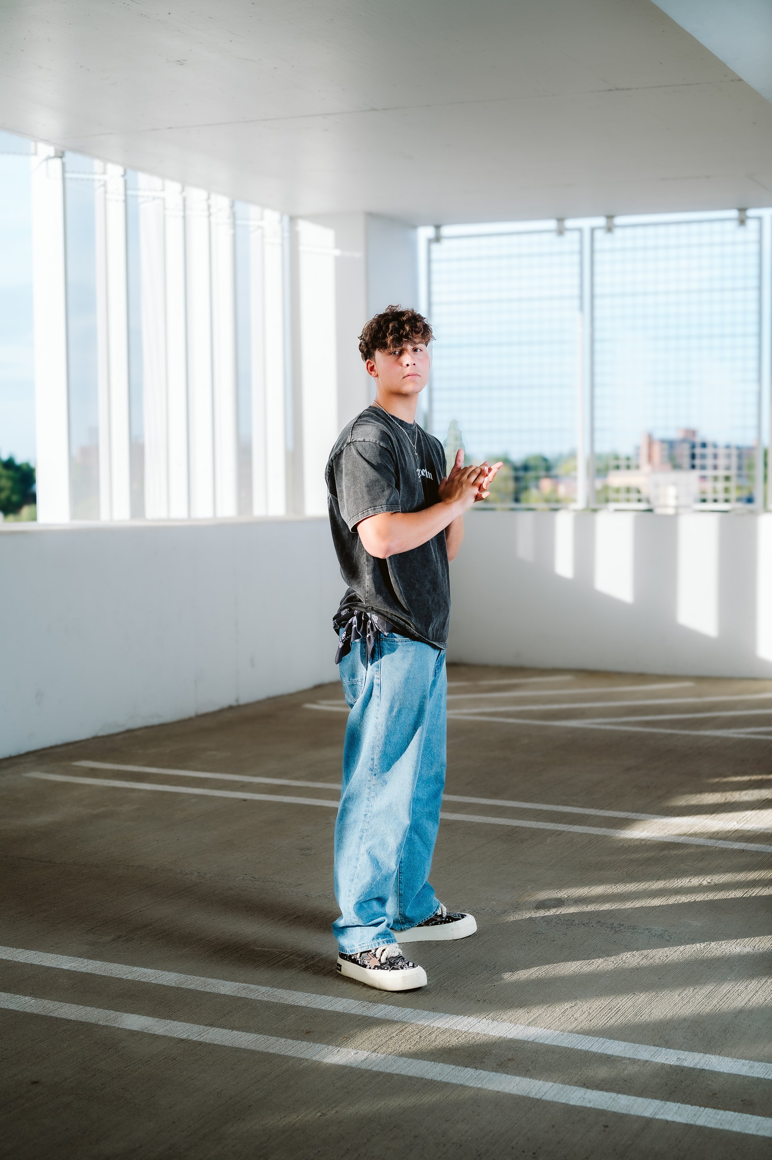 Full-body senior portrait photographed in Vancouver Washington with a minimalist urban backdrop and relaxed posture.
