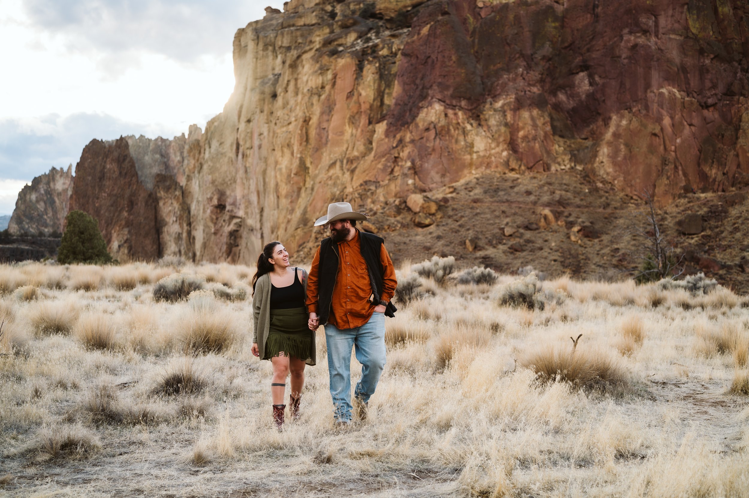 Outdoor couple photography session in a scenic desert-style landscape with rocky cliffs, captured by a Vancouver Washington photographer.
