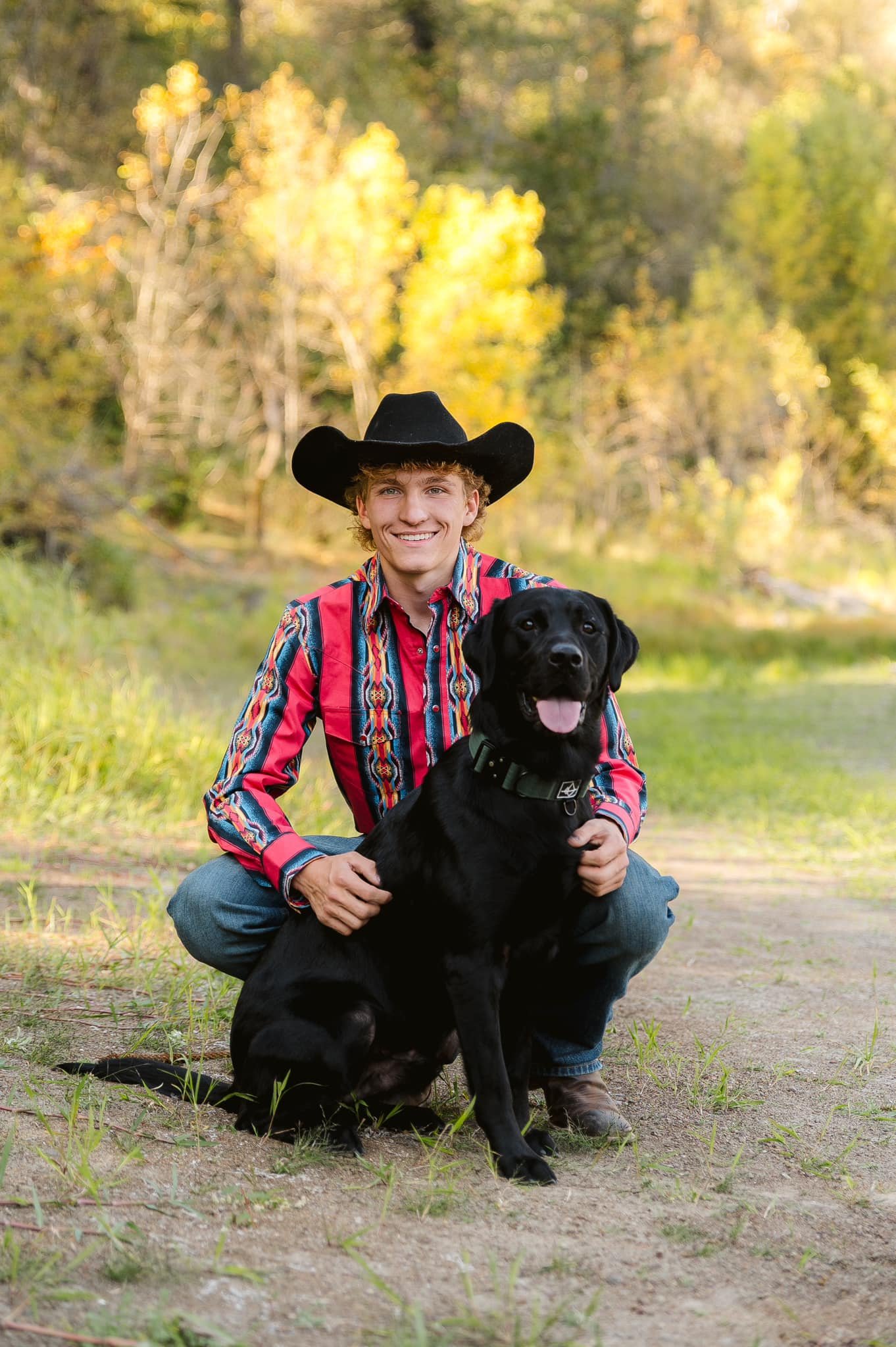 Young woman with dark wavy hair and makeup posing under a flowering tree with pink and white blossoms.