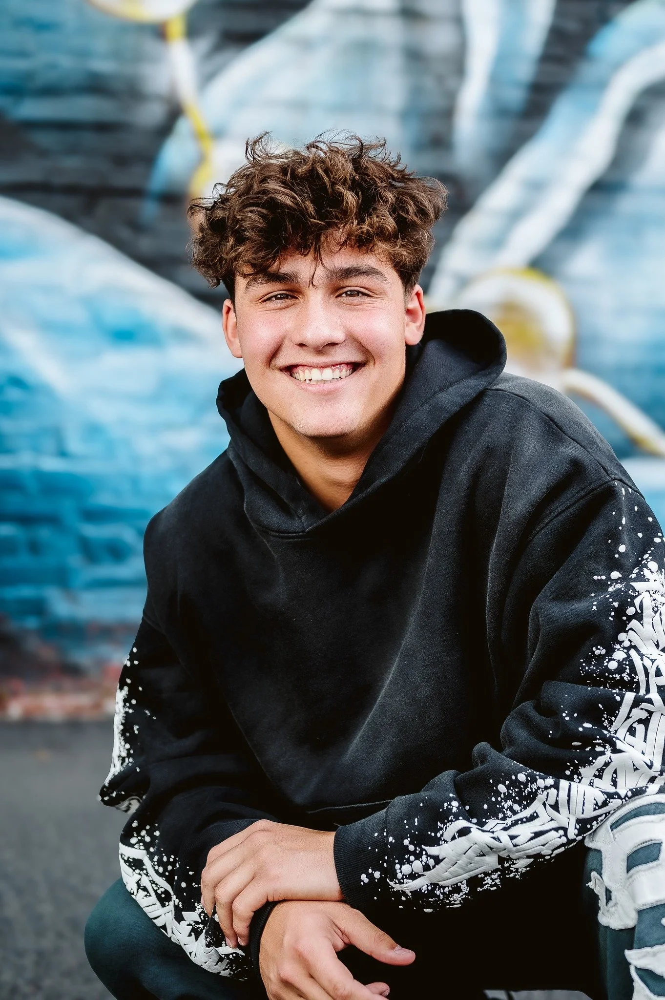 Male high school senior portrait in front of a colorful graffiti mural in Vancouver WA