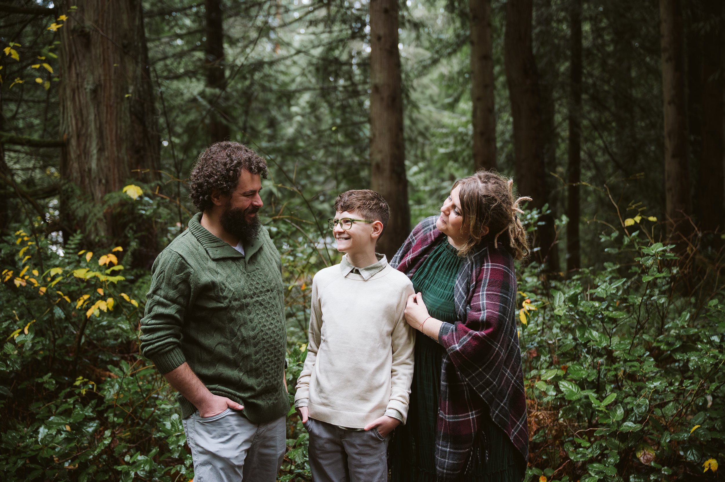 Family of three standing together in a forest during an outdoor family photo session