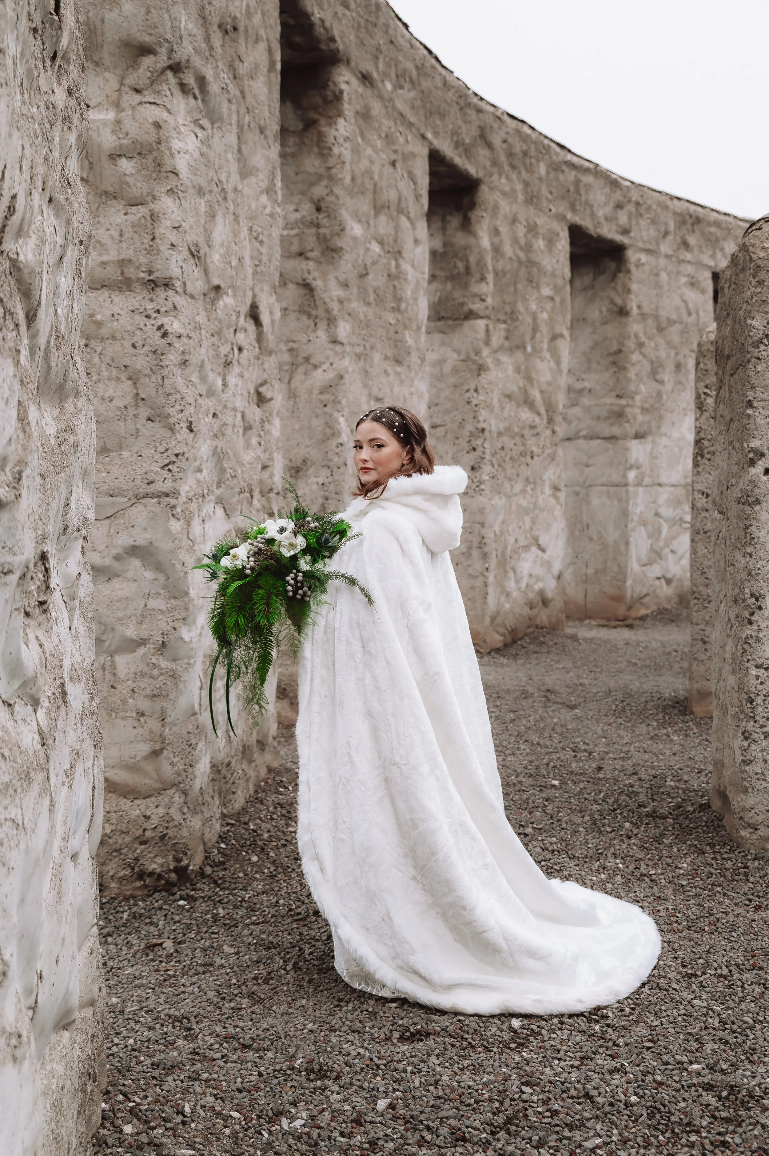 winter bride wearing white coat over wedding dress during intimate outdoor oregon elopement in cold weather
