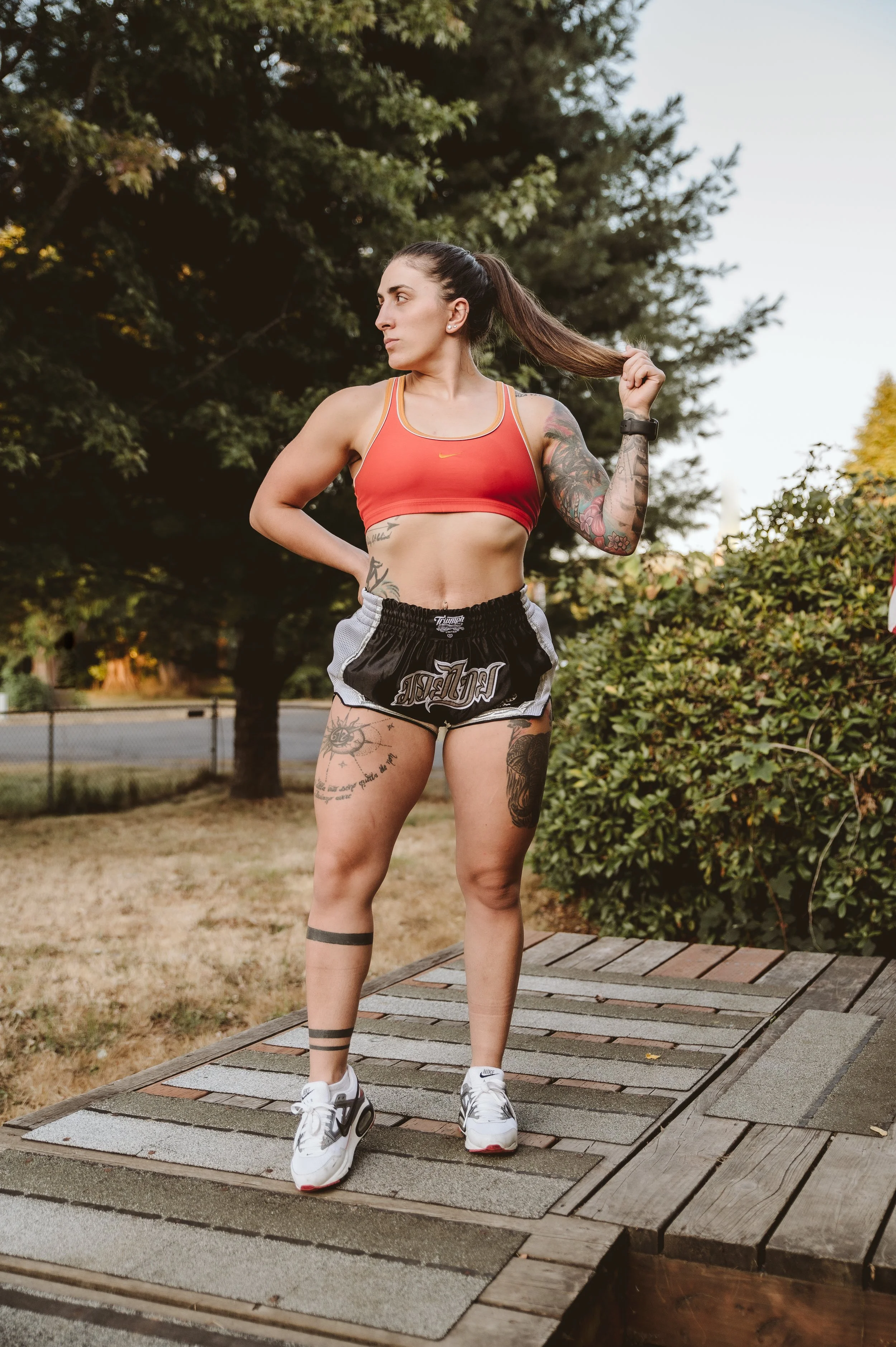 Outdoor lifestyle fitness portrait of a young woman standing on a wooden platform surrounded by trees, photographed by a Vancouver Washington photographer.
