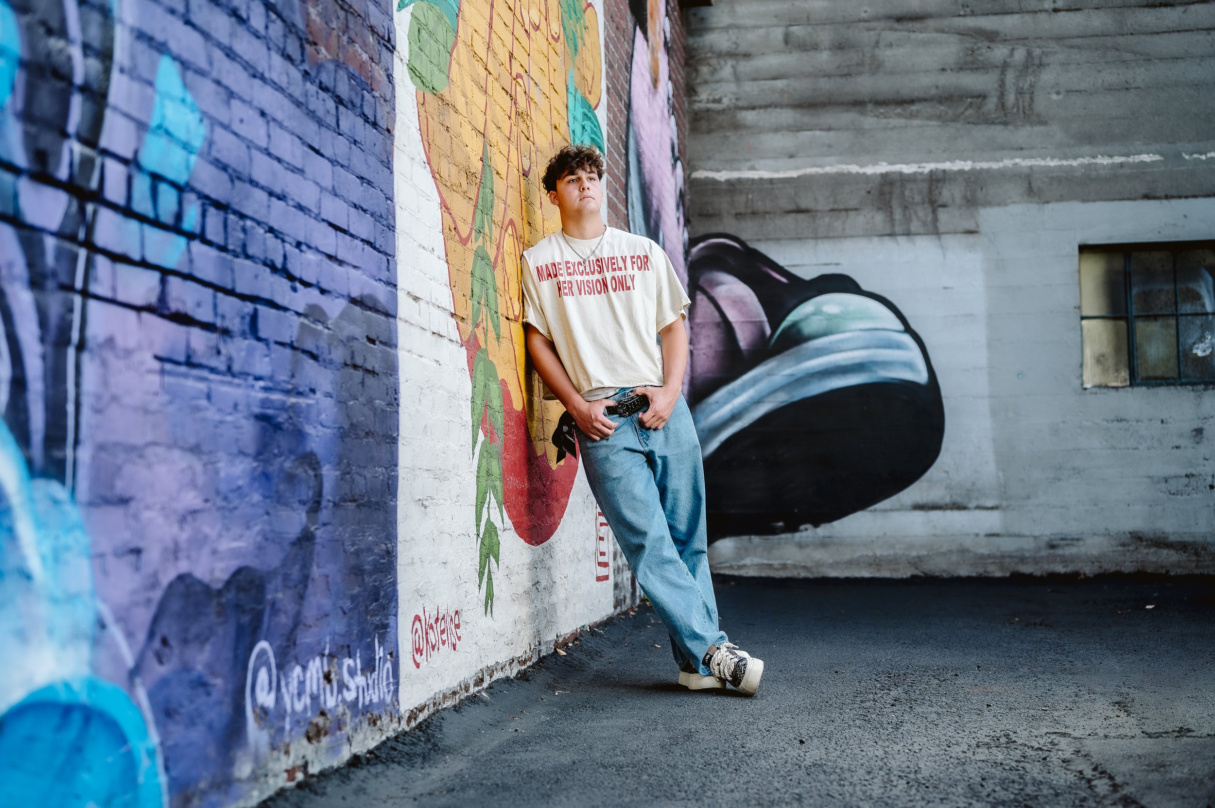 High school senior boy posing against colorful urban mural during senior photo session in Vancouver Washington
