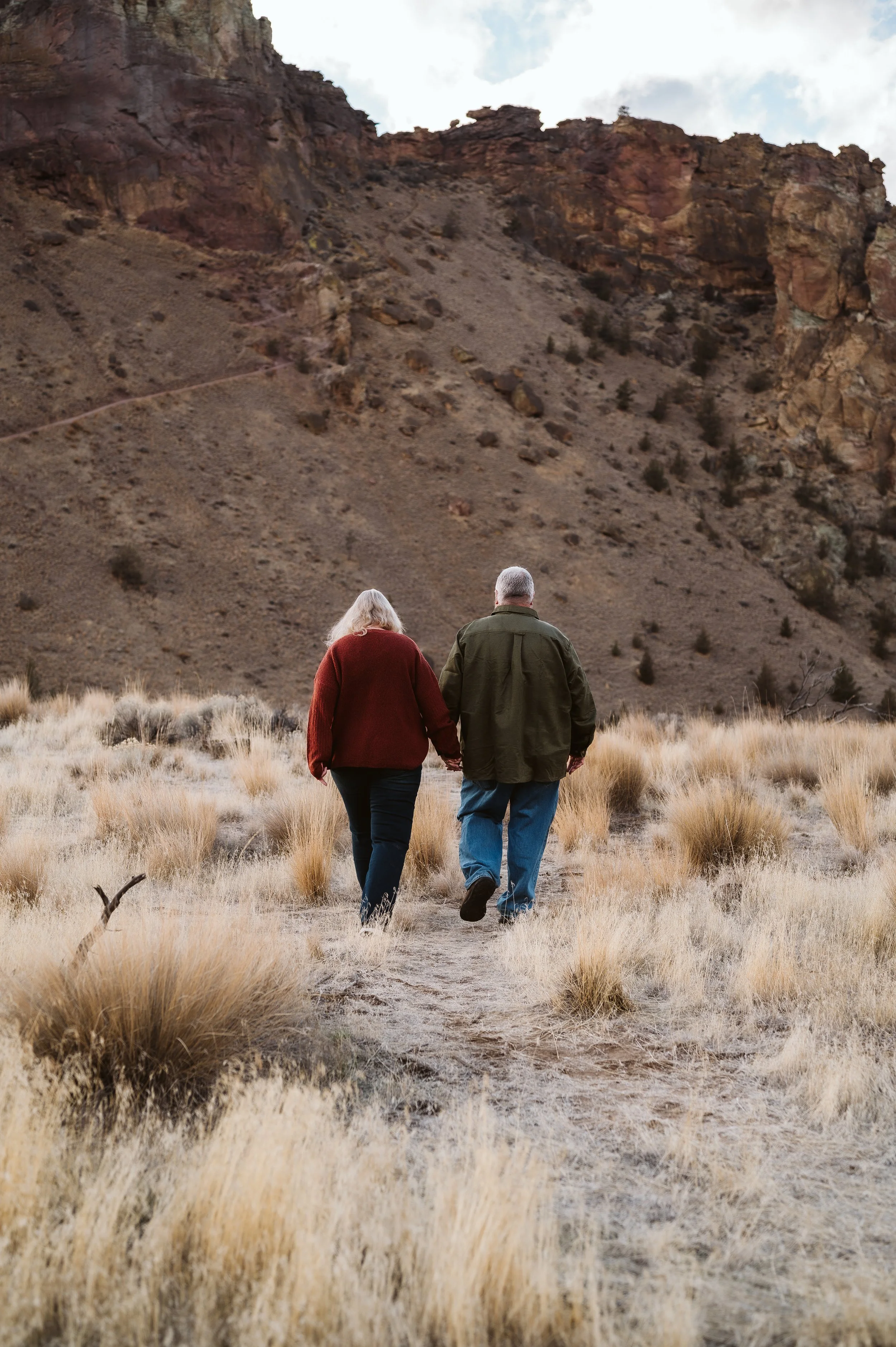 Romantic lifestyle couple photography of an older couple walking hand in hand through a scenic outdoor landscape, photographed by a Vancouver Washington photographer.
