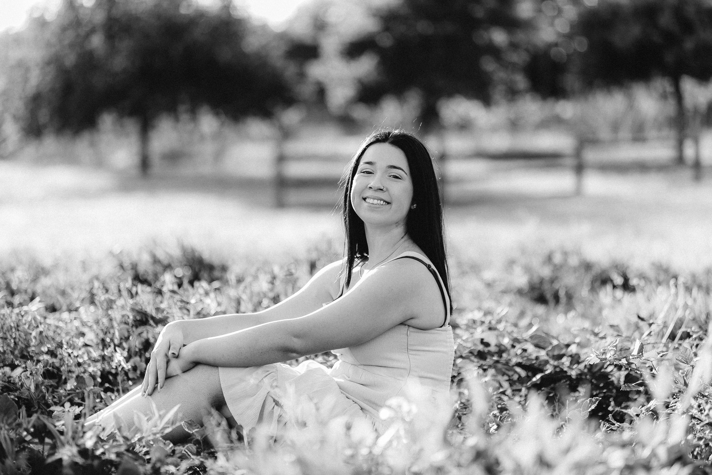 High school senior in a dress sitting outdoors for a black and white senior portrait in Vancouver WA