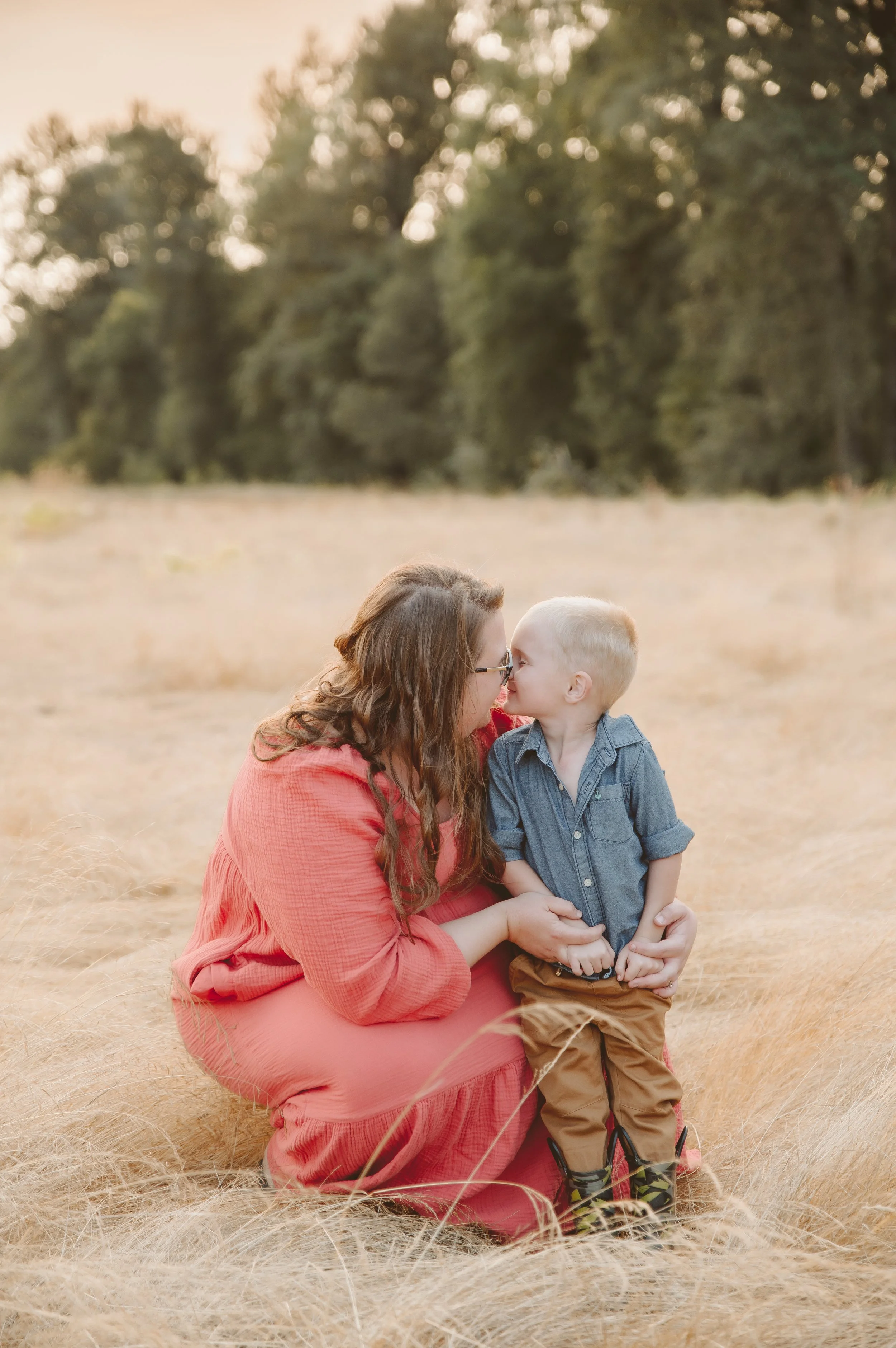 Emotional parent and child portrait of a mother and son sharing a quiet moment in tall grass at sunset, photographed by a Vancouver Washington family photographer.
