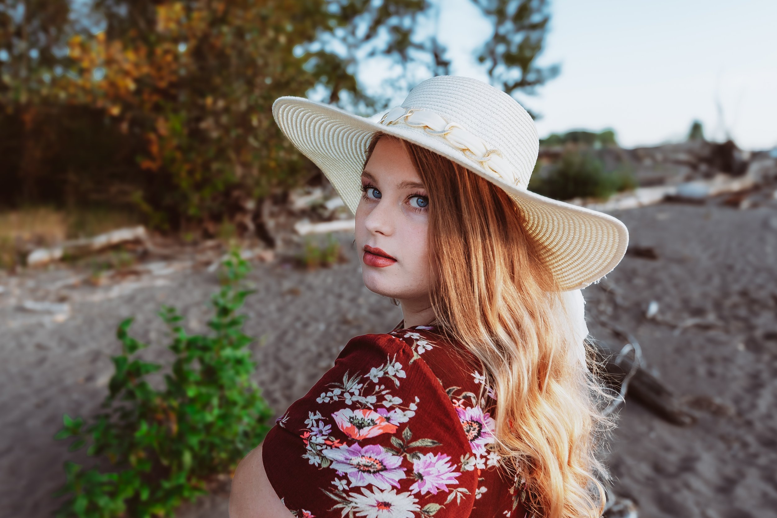 A relaxed high school senior portrait captured by a Vancouver Washington senior photographer, featuring a graduating senior in a floral dress at a natural beach location.
