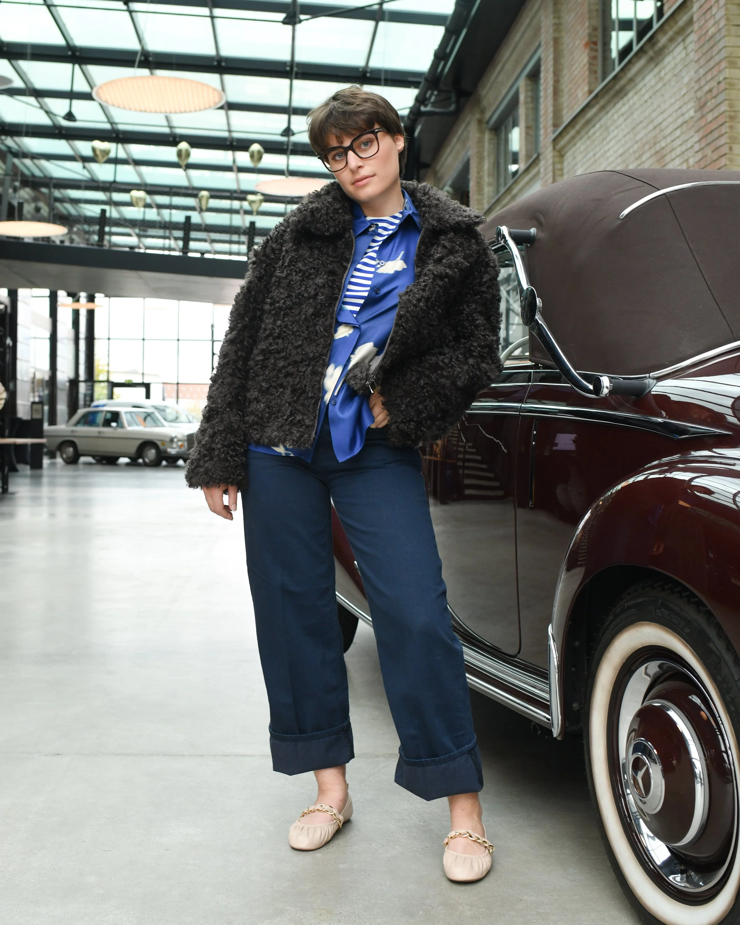 Frau mit dunkelblauer Jeans, blauer Seidenbluse und dunkelbrauner Ksucheljacke