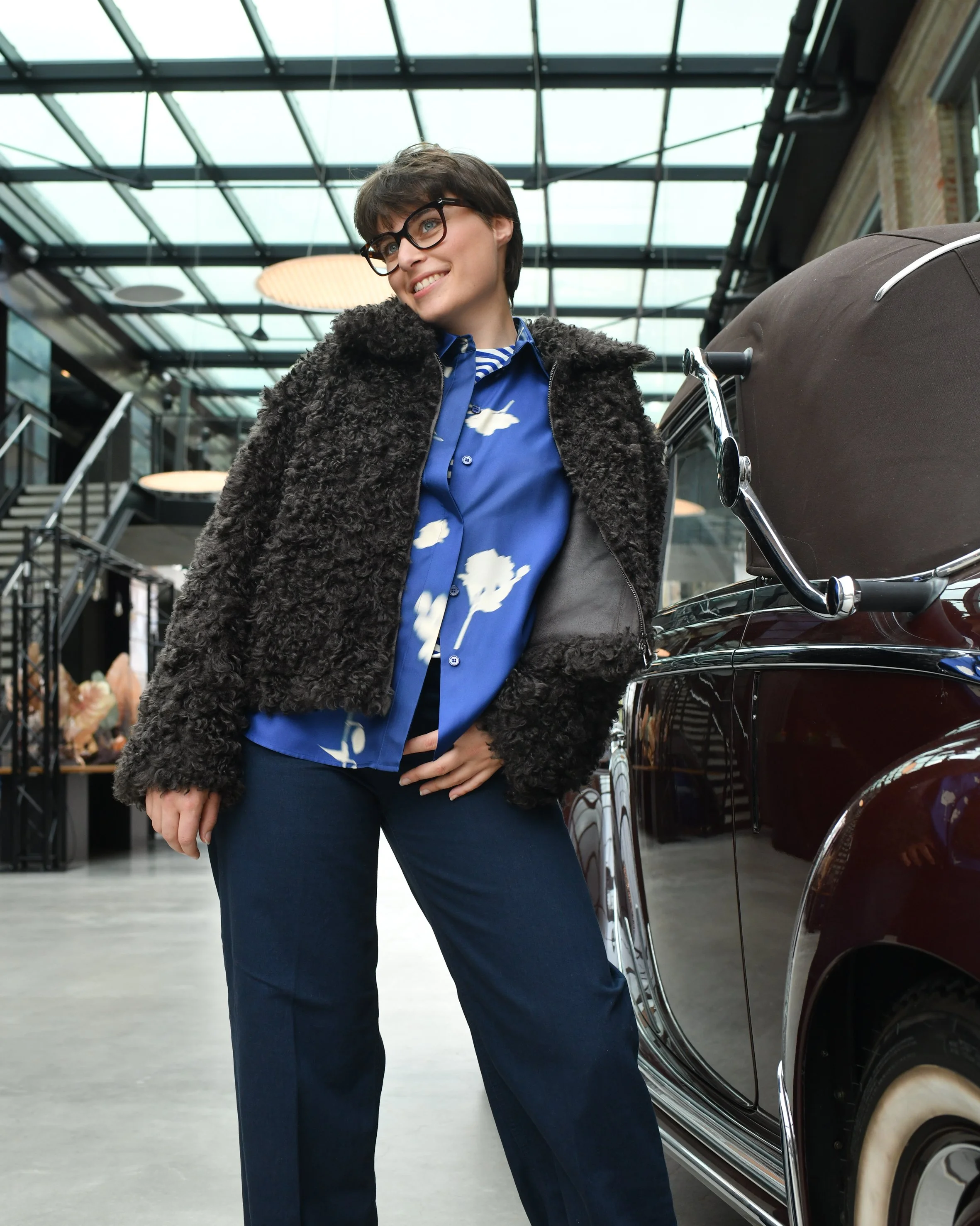 Frau mit dunkelblauer Jeans, blauer Seidenbluse und dunkelbrauner Ksucheljacke