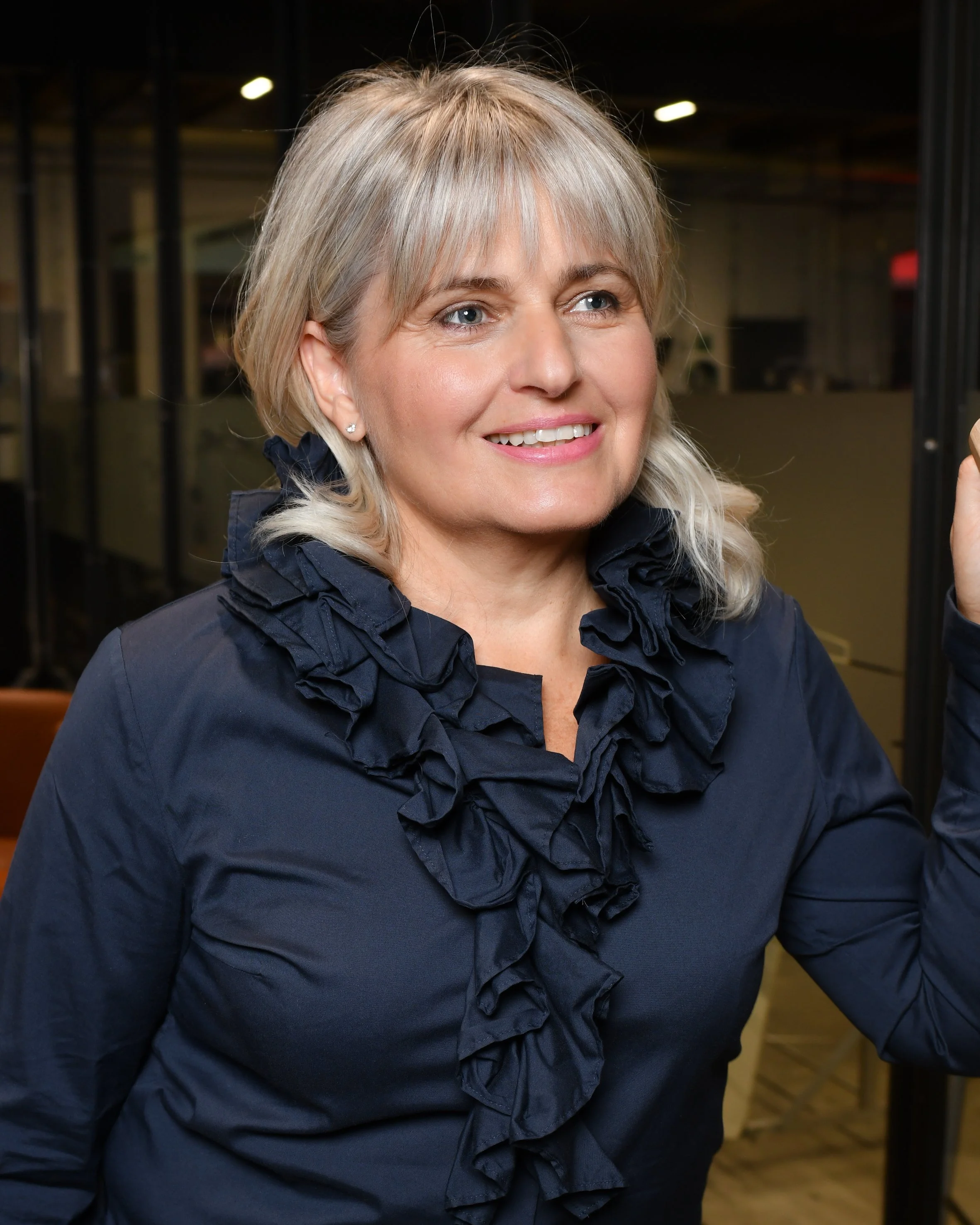 Frau mit dunkelblauer Bluse, mit Rüschen am Dekolthe